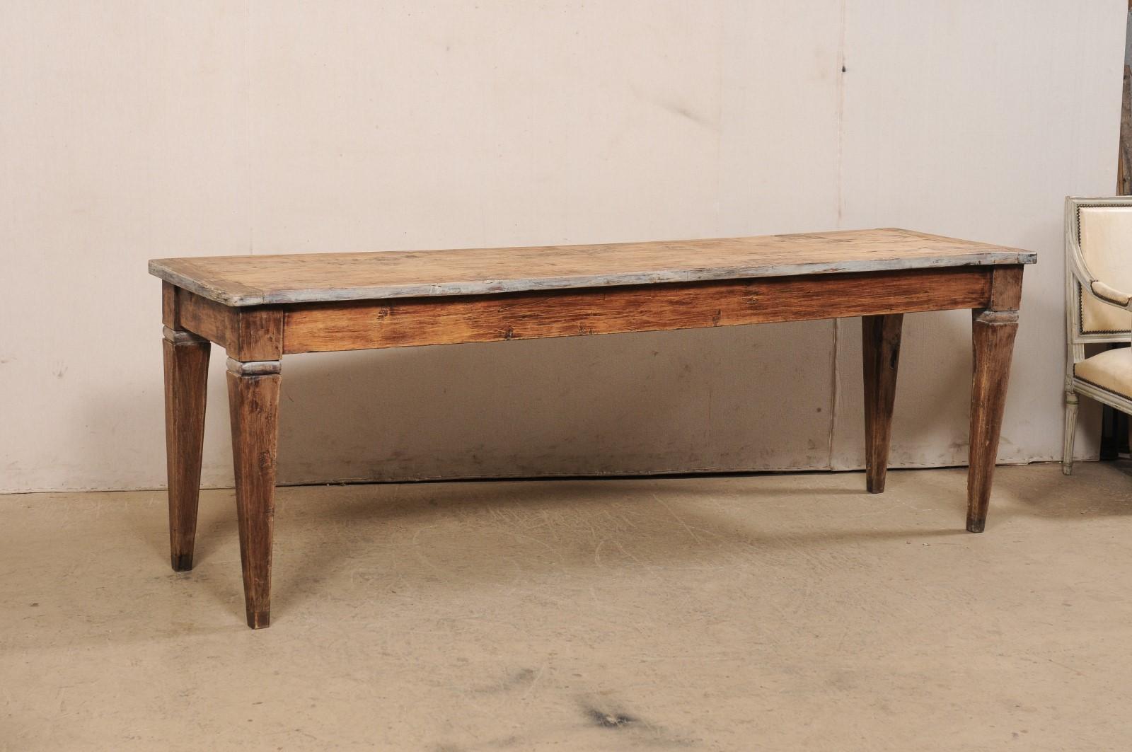 An Italian wood console table, approximately 7.75 feet in length, from the 18th century. This antique table from Italy has a long, rectangular-shaped top, which slightly overhangs the apron below (which is clean and linear), and is presented upon