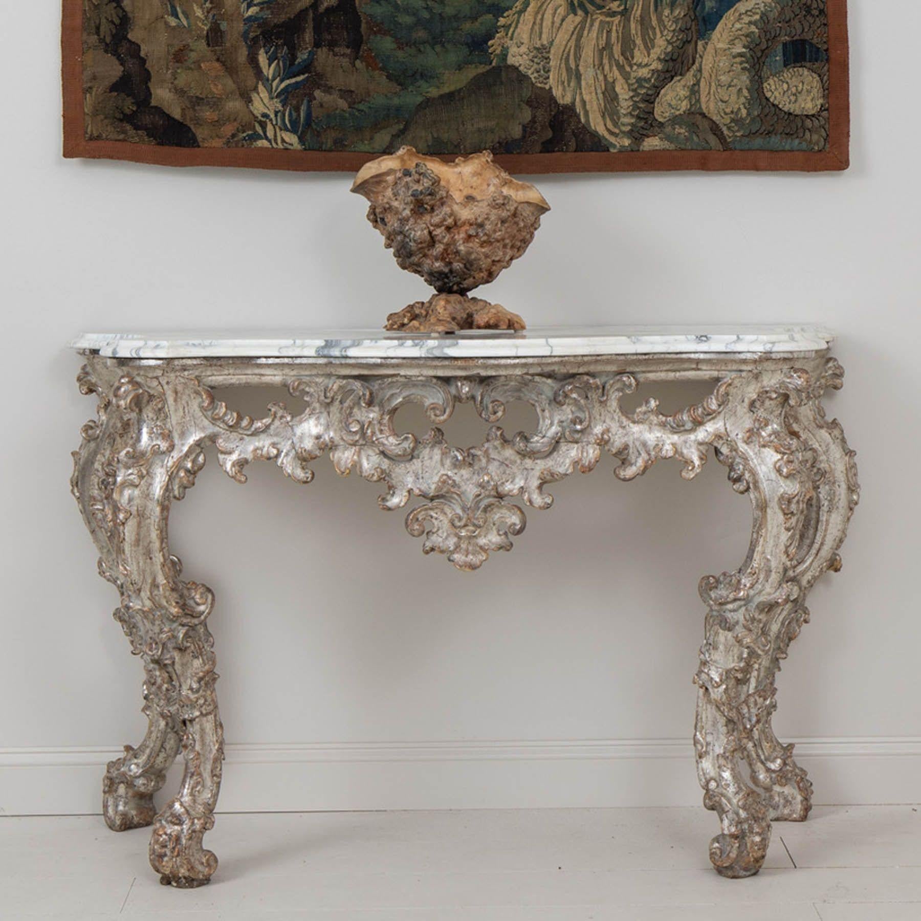 An Italian console in original parcel silver leaf beautifully carved with an Arabescato marble top from Tuscany, 18th century, circa 1750. Shaped marble top. Exceptional pierced, arbalest shaped frieze with elegant foliate carvings that continue