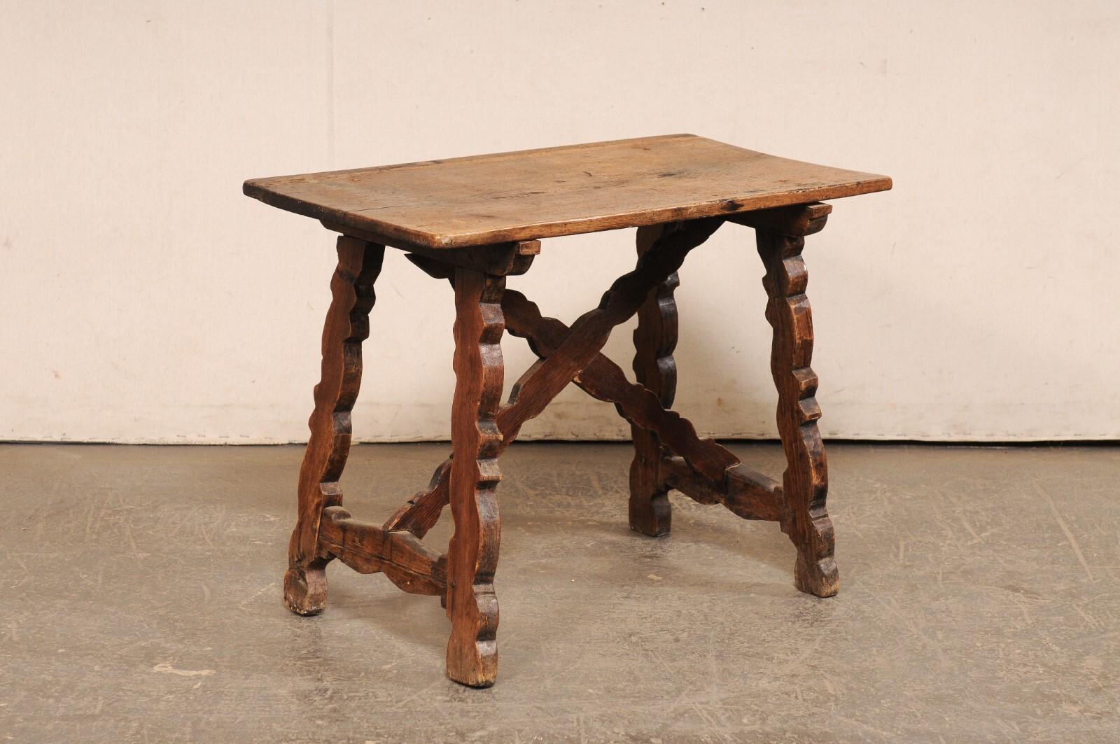 An Italian carved-wood occasional table, with trestle legs and x-stretcher, from the 18th century. This antique table from Italy has a rectangular-shaped wooden board top, which is supported with a pair of sinuously-carved, and inwardly canted,