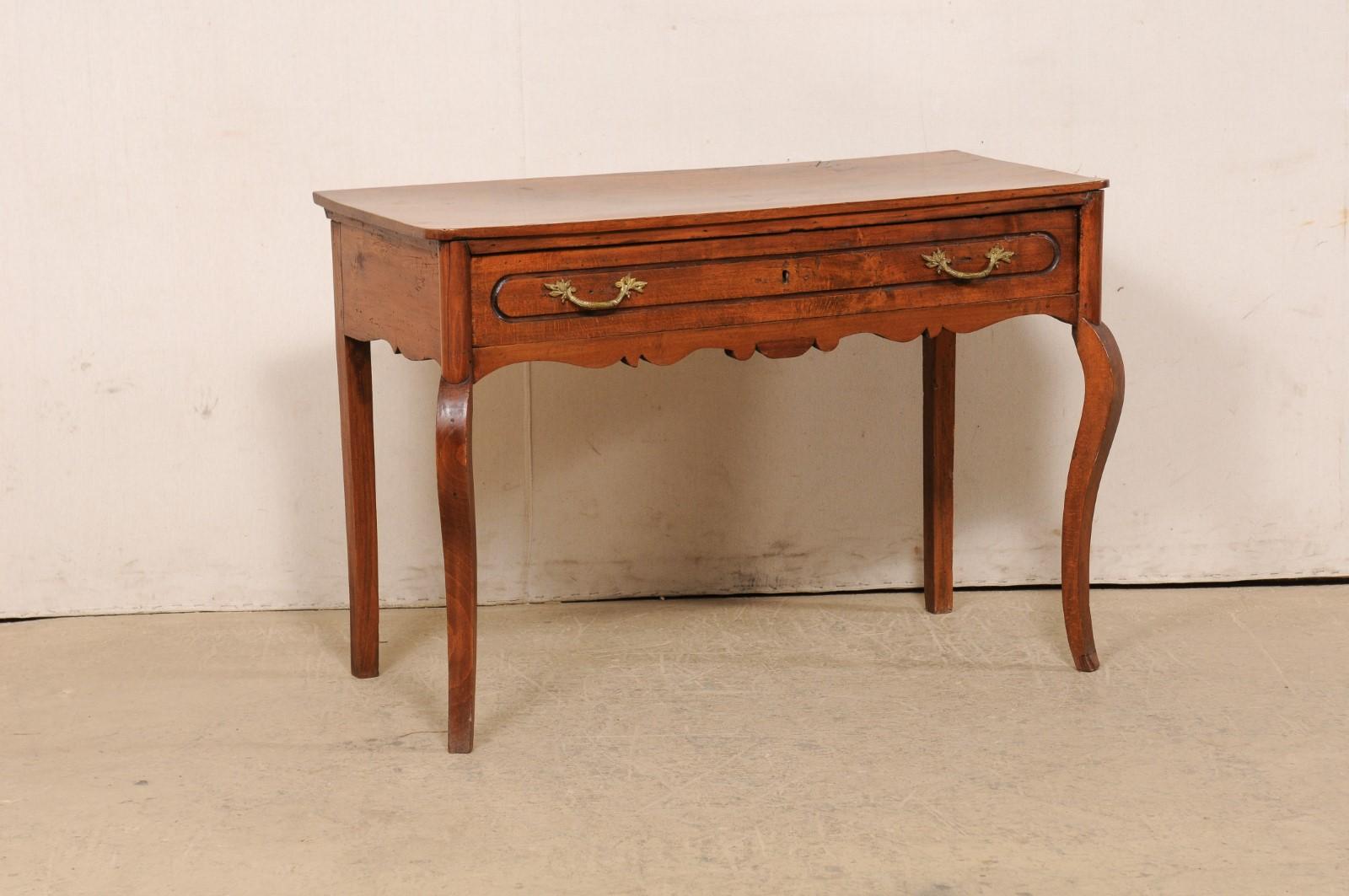 An Italian walnut table with drawer from the 18th century. This antique table from Italy has a rectangular-shaped top with softly-rounded front corners which rests atop an apron that houses a full-sized drawer along its front side, and has a nicely