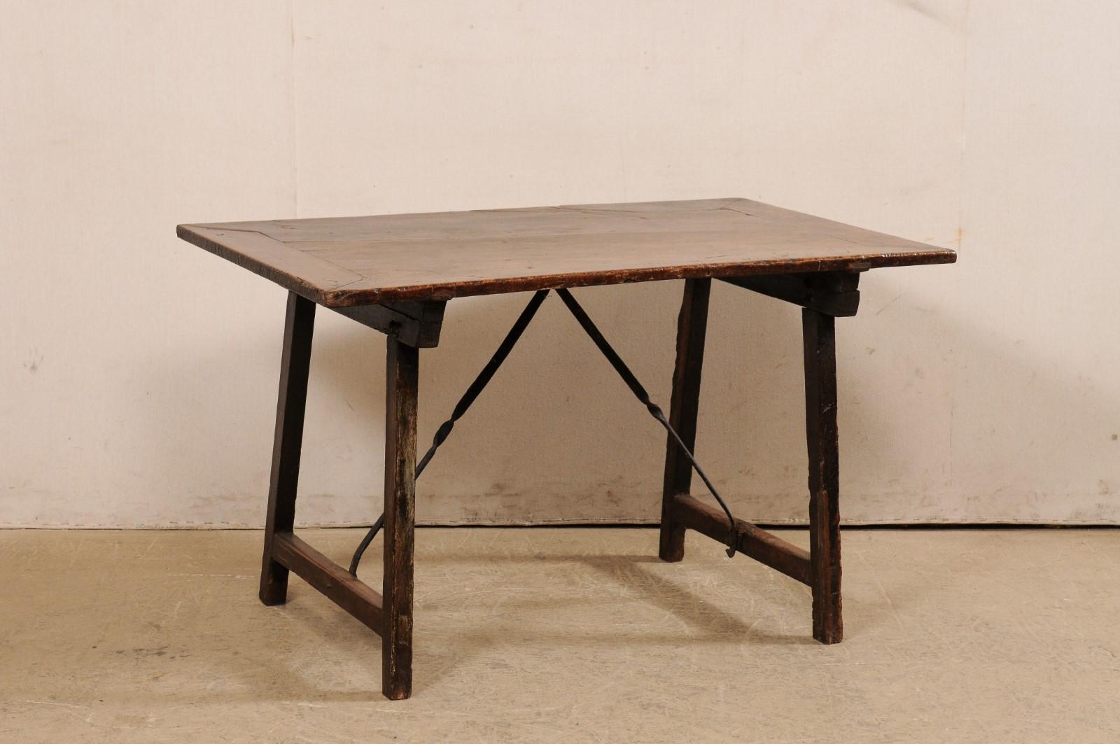 An Italian wood trestle-leg table with forged-iron stretcher bars, from the 18th century. This antique table from Italy has clean, simple lines, and features a rectangular-shaped top, raised upon a pair of trestle sawhorse-style legs, with a wood