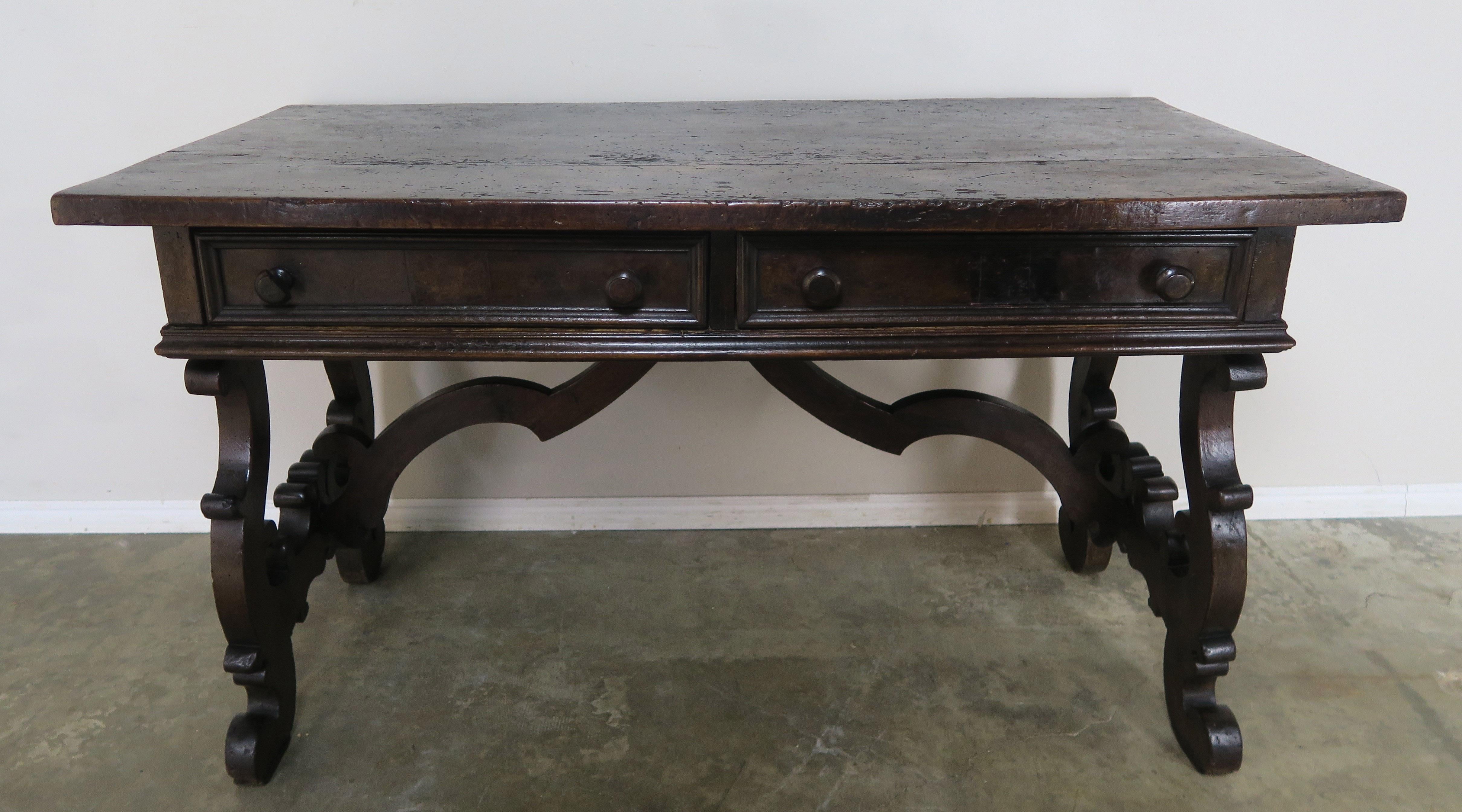 18th century Italian Renaissance style walnut writing table with two drawers. The table stands on two lyre shaped bases connected by a center stretcher.