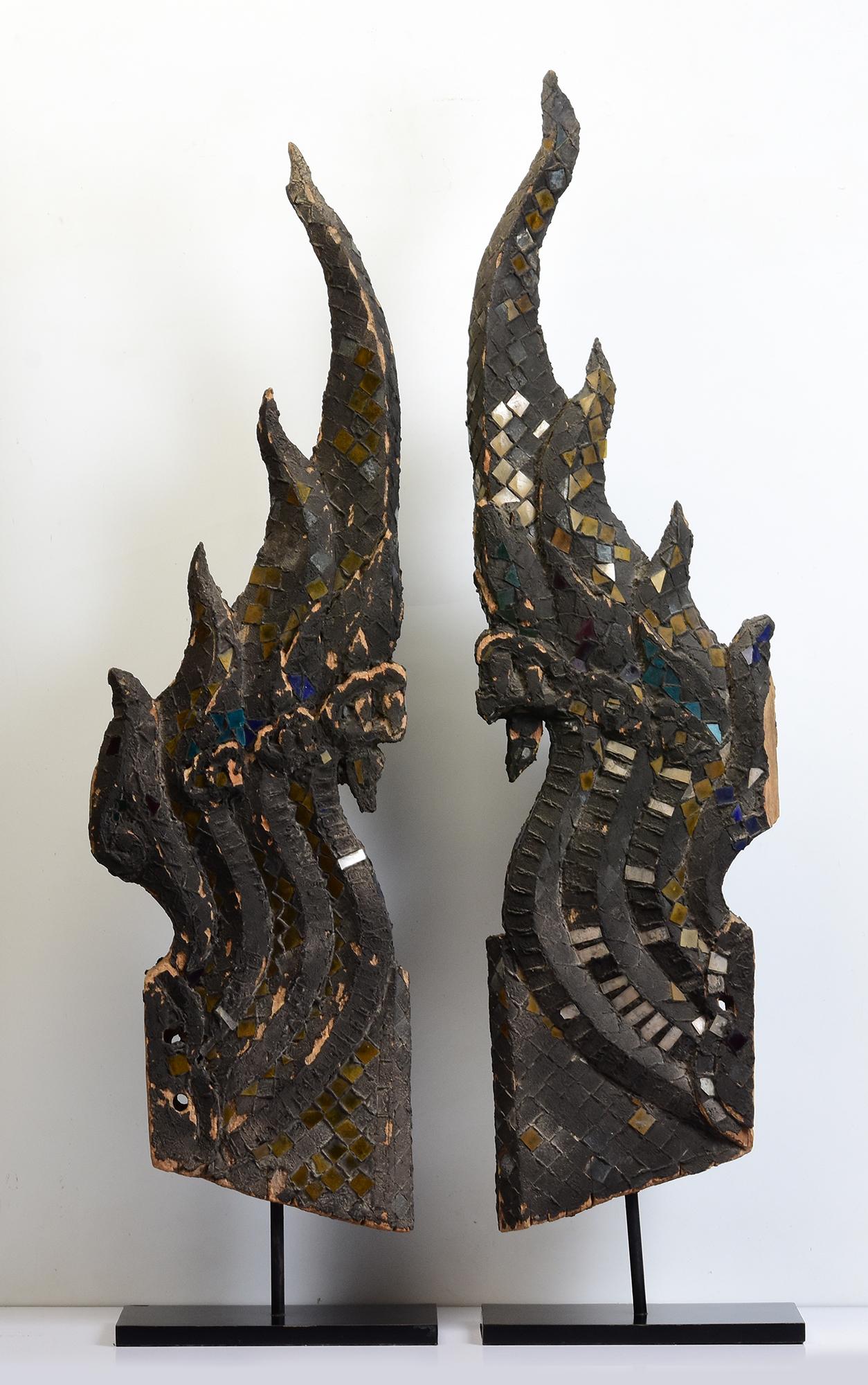 A pair of antique Thai wooden finial Naga carved on both sides and decorated with mirror-tiles, used for decoration on top of the temple's roof. 

Age: Thailand, Late Ayutthaya Period, 18th Century
Size of Naga only: Height 104 - 110 C.M. / Width 29
