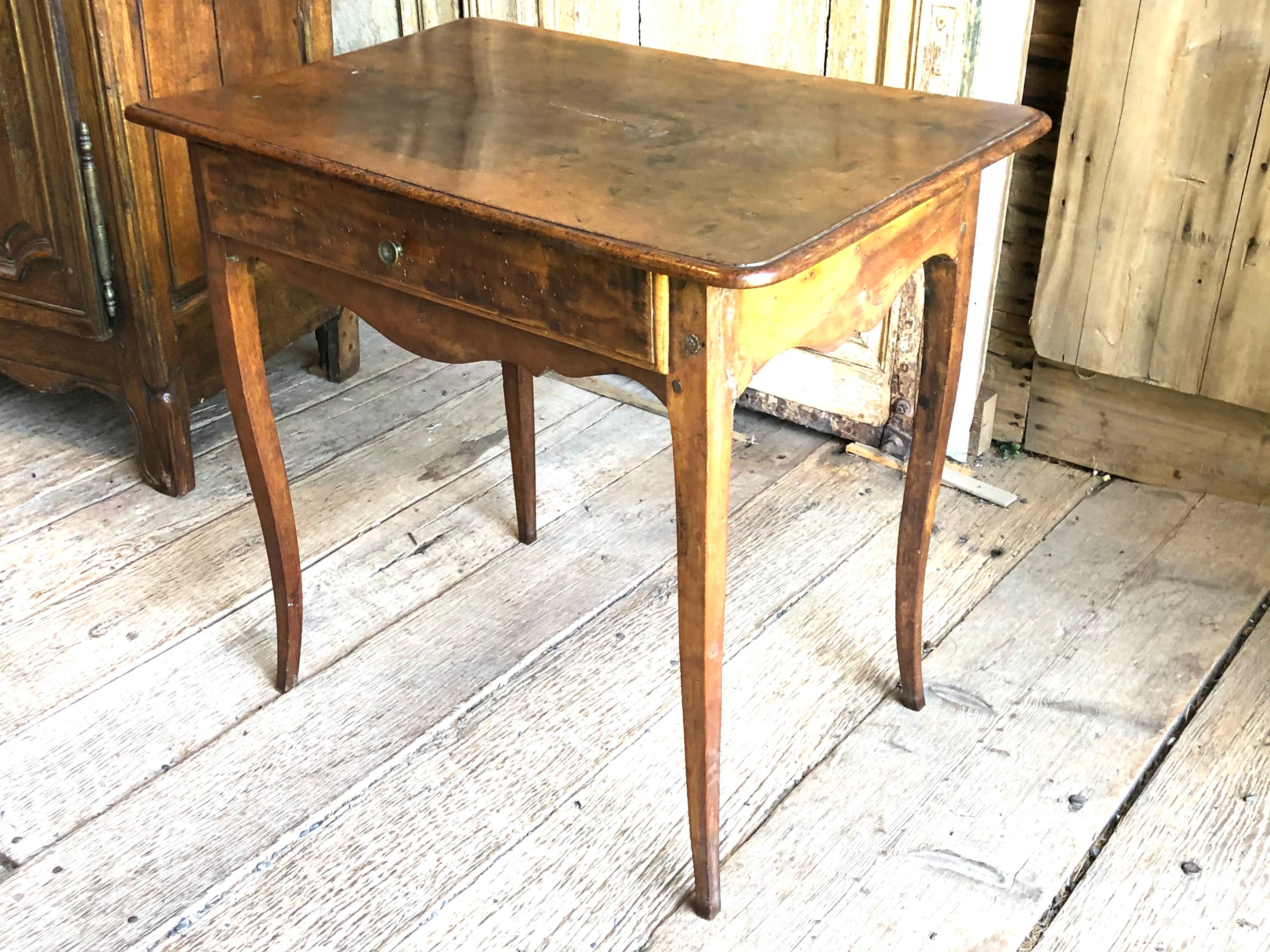 A mid 18th century Louis XV side table with drawer, in walnut, with scalloped apron on slender cabriole legs, circa 1760. Original brass drawer pull.
  