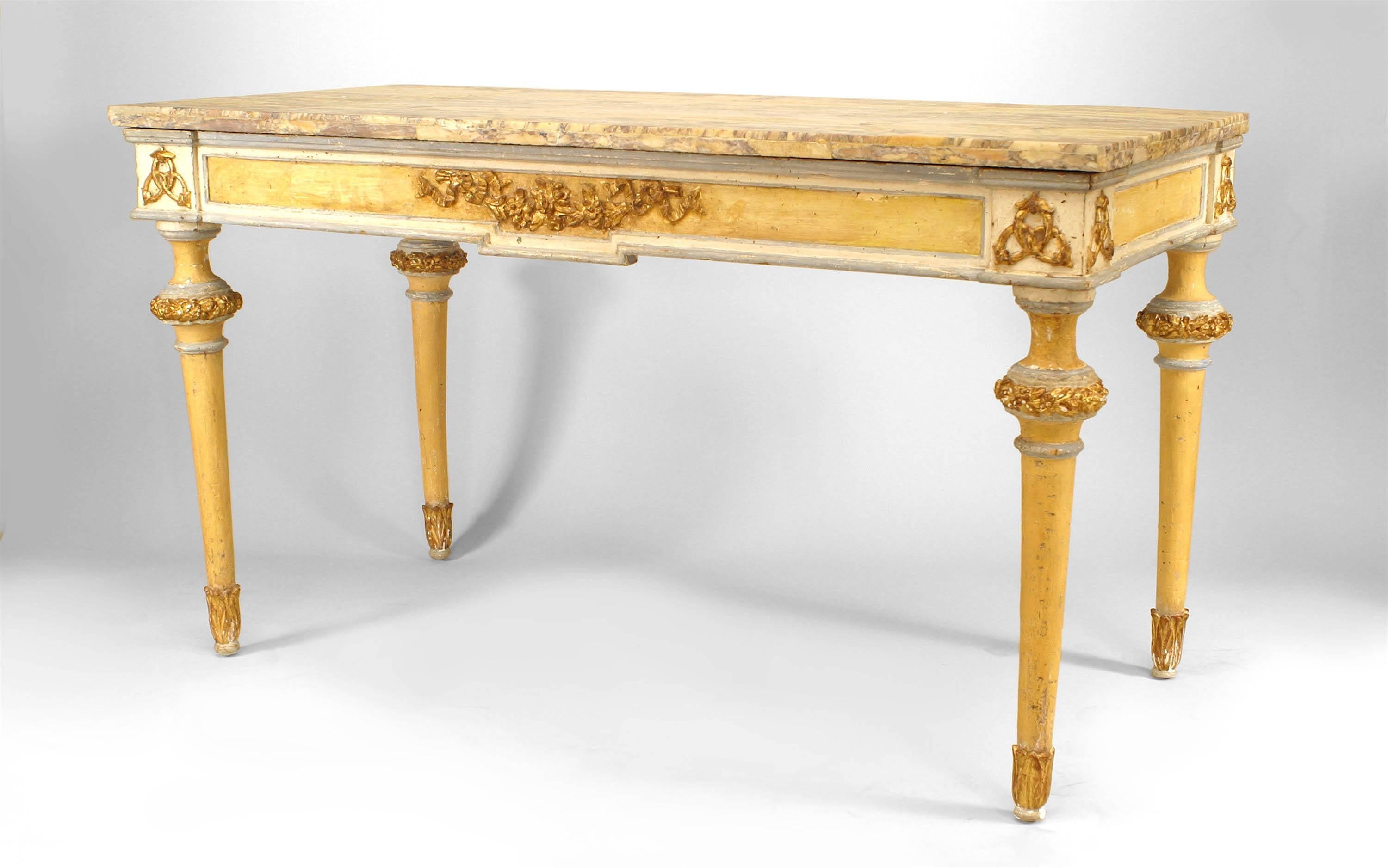 Italian Neoclassic yellow painted and gilt trimmed console table featuring a marble top, a central gilt floral motif flanking interlocking oval mounts, and tapered round legs.