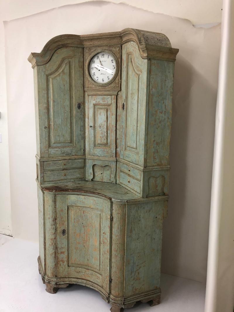 Beautiful hand scraped original paint corner cupboard. An impressive piece with two upper cupboards, four drawers and concave lower cupboard. the center of the upper section is a clock, the pendulum and weights are included. the clockworks are not