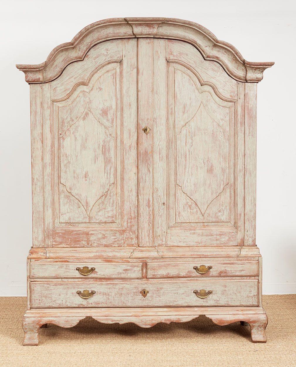 An impressive cabinet in original dry-scraped cream/grey paint, consisting of a wonderful overhanging baroque arched cornice on a two door cupboard with single adjustable shelf above a lower stepped plinth of four drawers with a scalloped apron. 