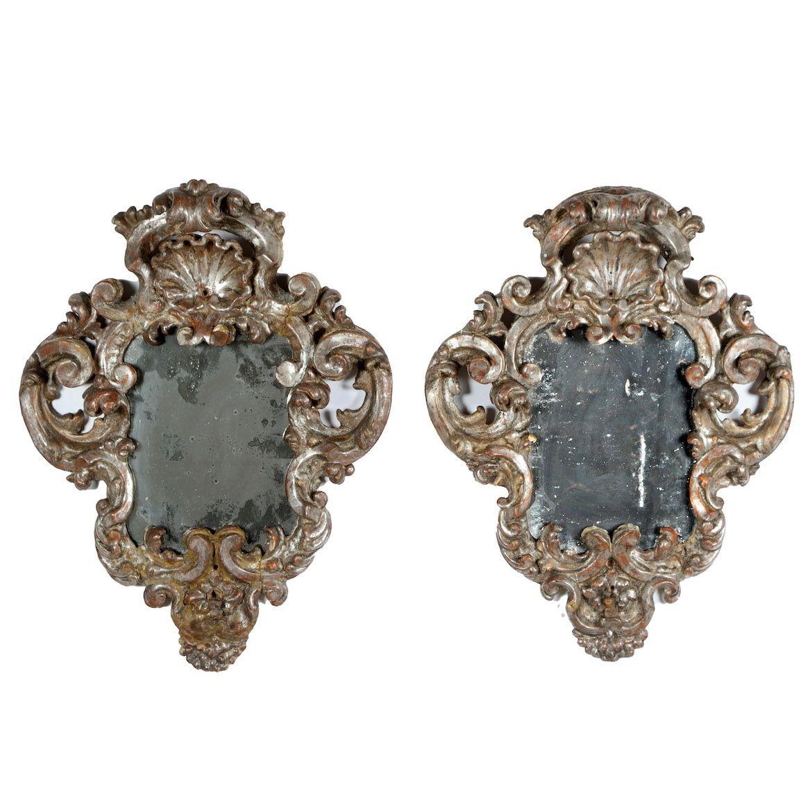 An exceptional pair of Italian Baroque mirrors with original silver leaf and mirror plates. Richly carved, raised crest in shell motif with scroll motif that extends down around each mirror.