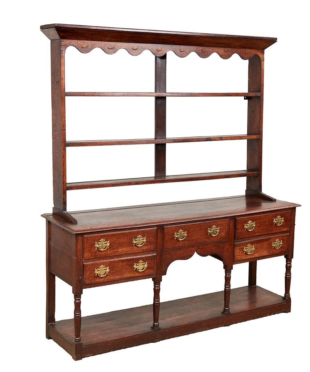 A mid-18th century dresser with rack with glowing patina in quarter sawn oak having a seven section divided rack with a wavy edge cornice, sitting on a molded edge top on six turned legs with a bank of double drawers to each side of a central drawer