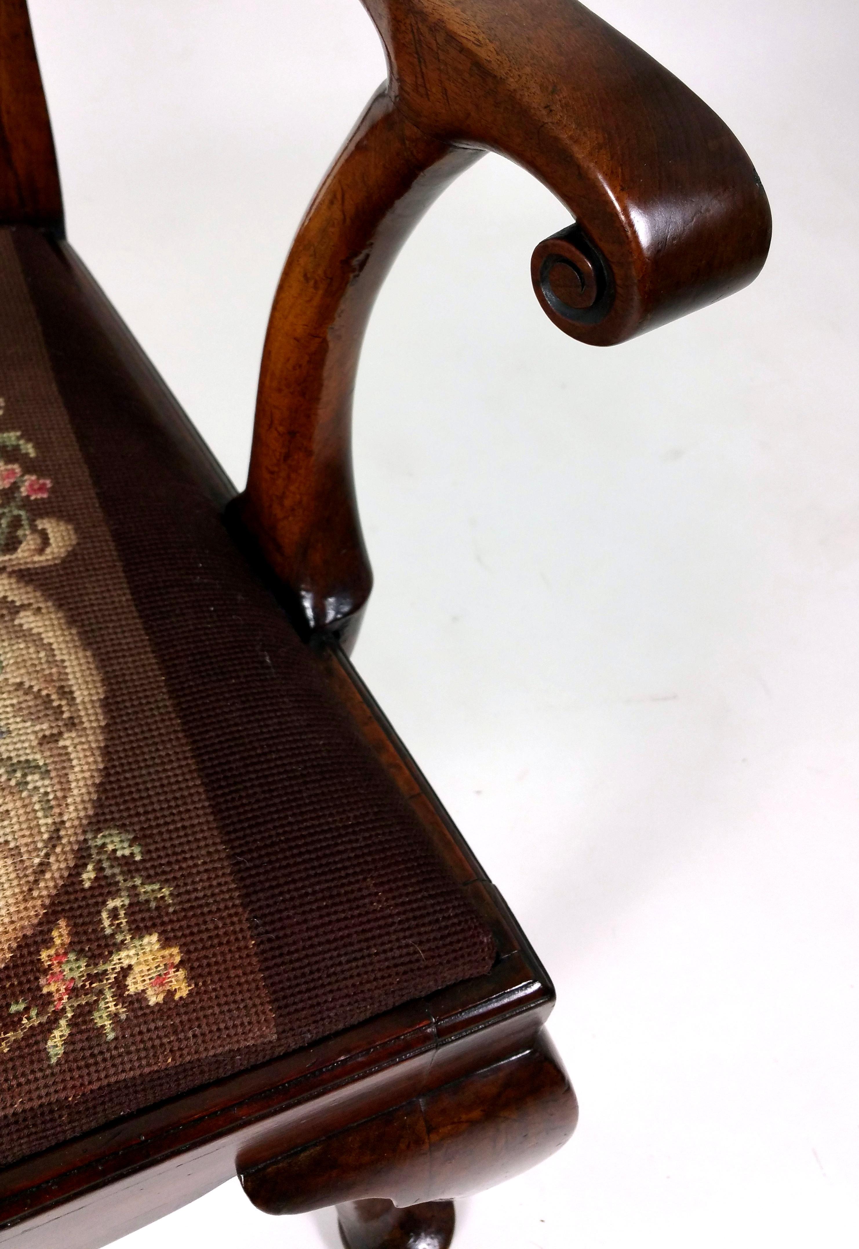 This very handsome and fine quality 18th century solid walnut splat back elbow chair features front cabriole and swept back legs with shaped arm supports. The chair has a drop in seat with an old, but not original, tapestry cover in very good