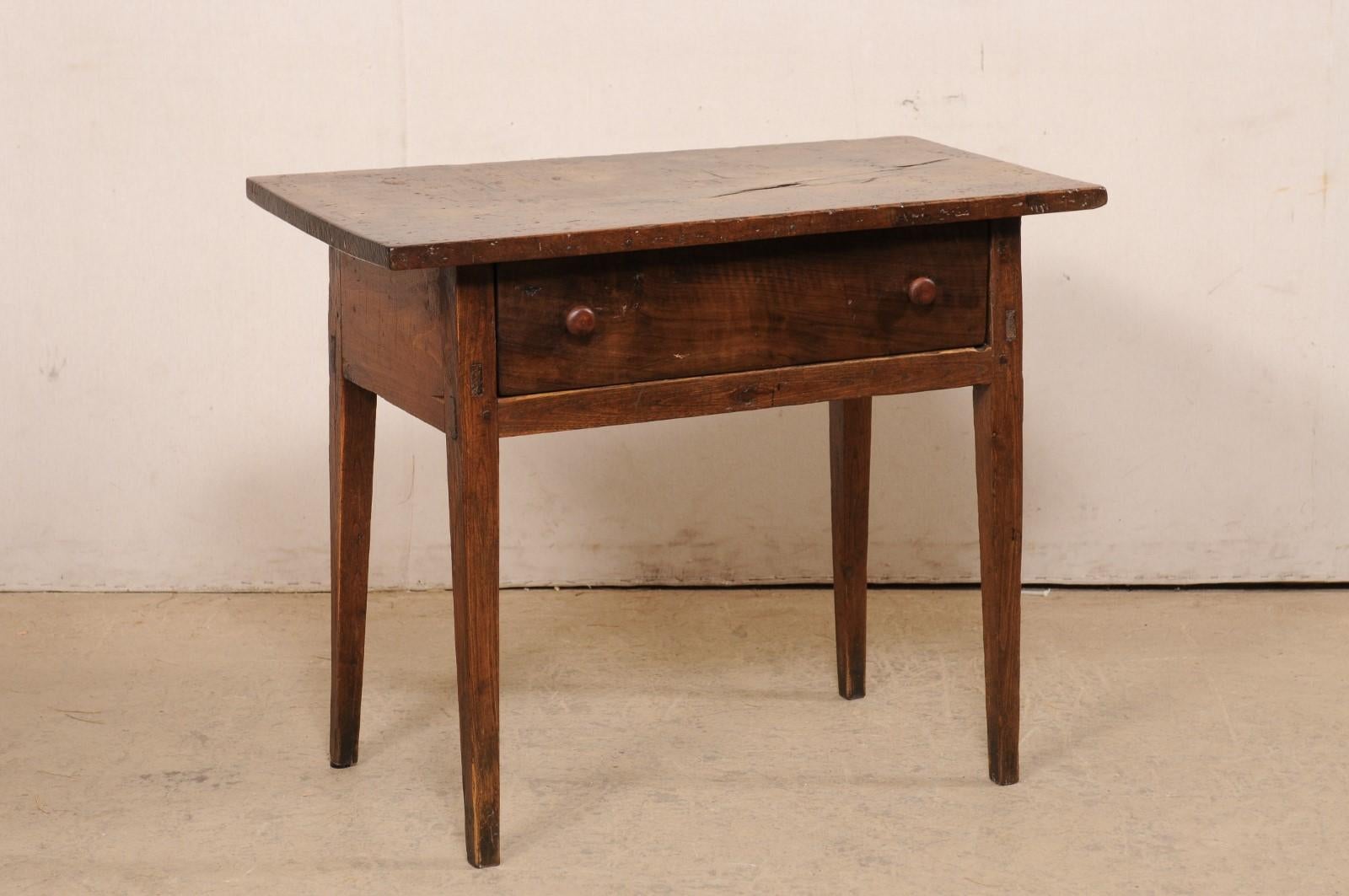 A Spanish carved-walnut wood occasional table with single drawer, from the 18th century. This antique table from Spain, designed with clean lines, has a rectangular-shaped top, which overhang the apron below that houses a single drawer at one long