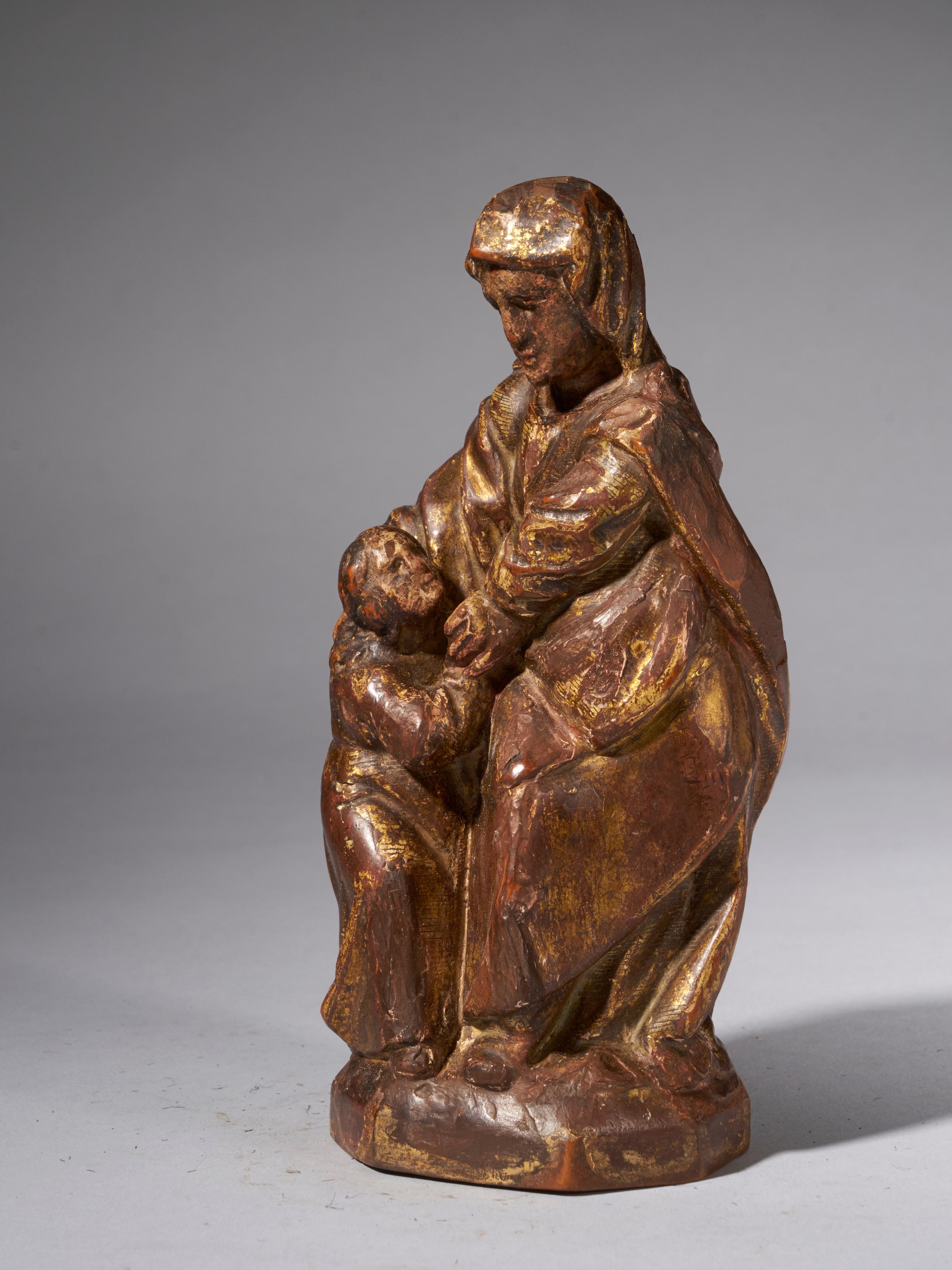 This 18th century wooden sculpture represents Mary looking down at Jesus by her side, sculpted in a block of wood, folk style. The folds of the robes and the creases in the faces are clearly visible. The sculpture was polychromed and show nice signs