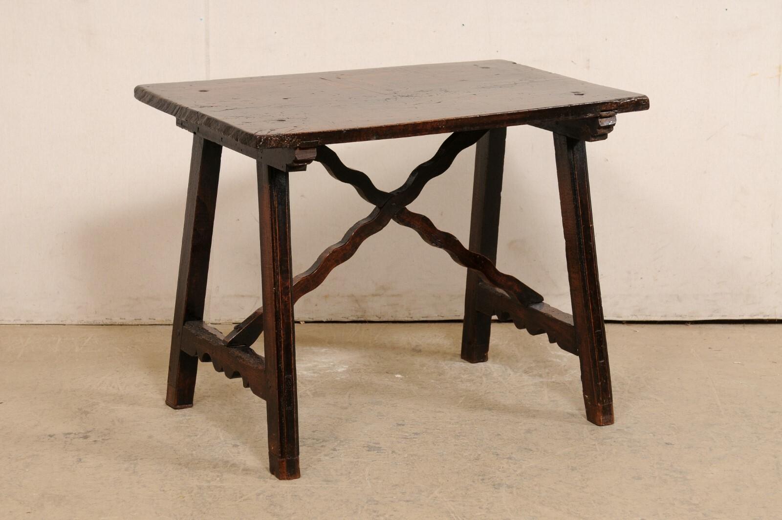 A Spanish carved-wood occasional table from the 18th century. This antique table from Spain has a rectangular-shaped and beautifully aged wood top, and raised upon a pair of saw-horse style trestle legs. The legs have a clean design, with side