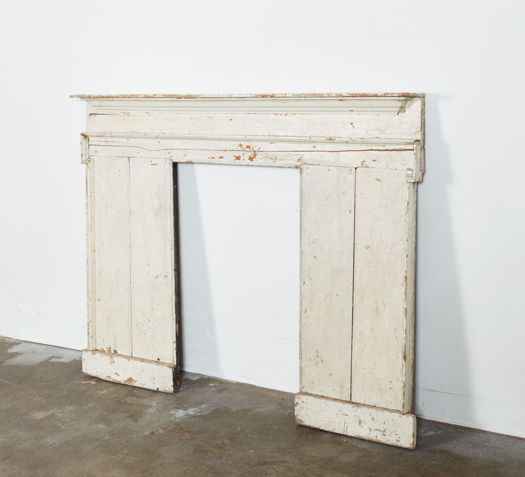 An historic chimneypiece or fireplace surround removed from an 18th century Georgian kitchen in Spitalfields, London. This imposing piece retains old white paint and is made from hand sawn and planed pine panels in the form of two wide pilasters on