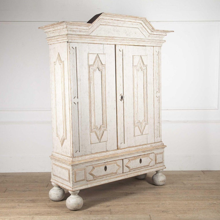 Beautifully carved Swedish cabinet from the Baroque period, circa 1740, painted a soft ivory/white with a decorative pediment and carved diamond detailing on the doors and sides.  Two large doors open to the interior which is painted in a variety of