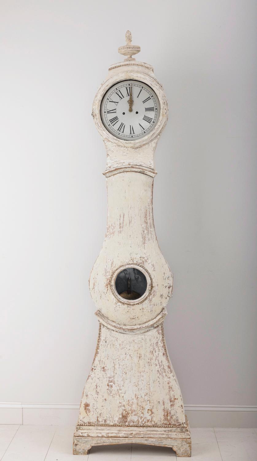 An 18th century Swedish Mora clock from the Gustavian period hand-scraped to reveal the original paint surface, circa 1790. Truly a stunning long case clock from top to bottom. The bonnet features a carved torch finial and the bottom of the