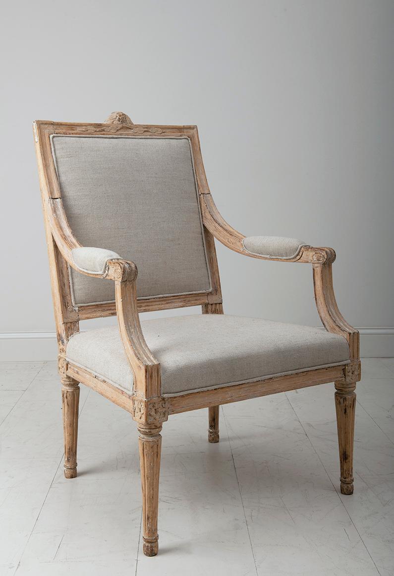 A Swedish armchair from the Gustavian period with a beautiful, natural patina, exquisitely carved leaf motif on the back, and newly upholstered in linen.