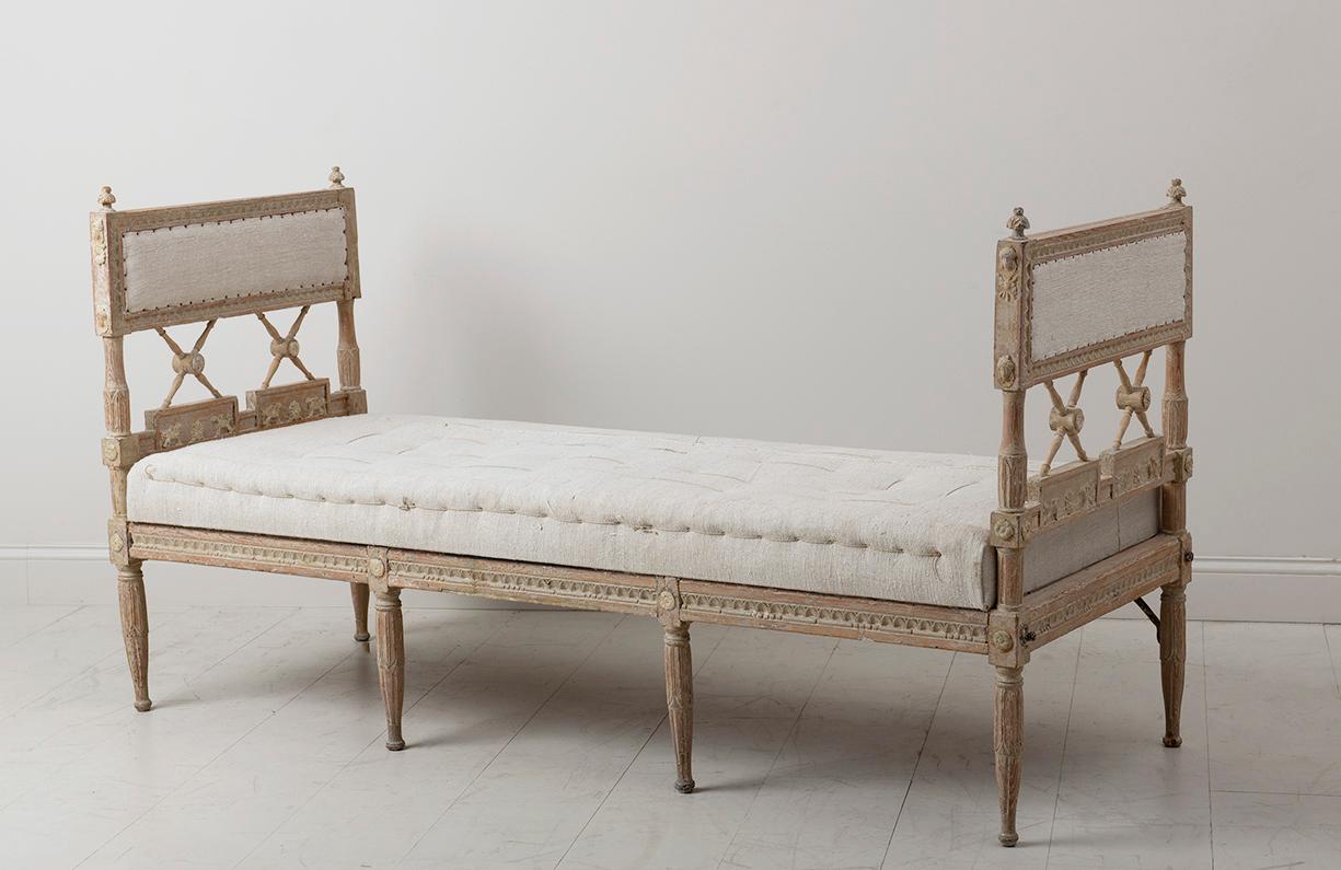 A rare 18th c. Swedish daybed from the Gustavian period hand-scraped to original paint, newly upholstered in linen. Circa 1790. Finished on three sides with egg and dart detail, Egyptian carvings on the sides, and carved sheaf of grain finials. 