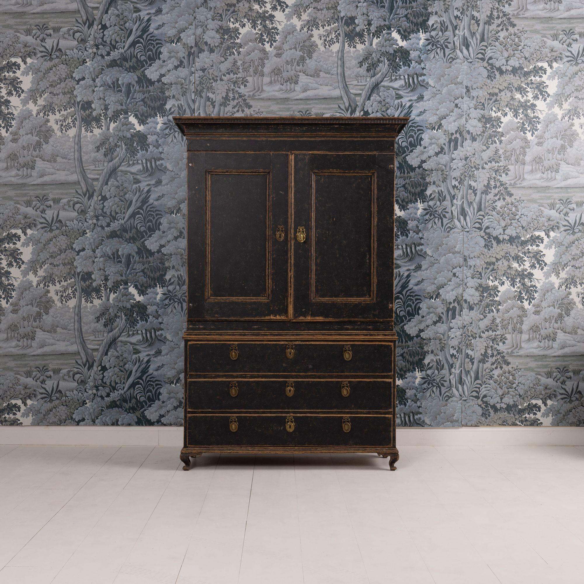 Prensa sueca de lino pintada de negro, de dos partes, del periodo Gustaviano, hacia 1780. Esta pieza está hecha en dos partes para facilitar su transporte (base inferior de la cómoda y armario superior). Este hermoso mueble tiene dos grandes puertas