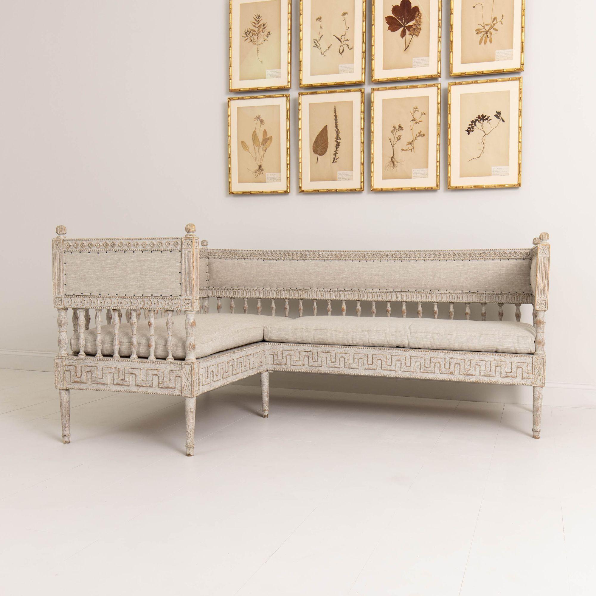 A rare period Gustavian corner banquette, profusely carved with unique variation of wood decor that is different on the inside and outside of the sofa, circa 1790. Newly upholstered in linen with nail head trim. Finished on all sides. A firm Maison