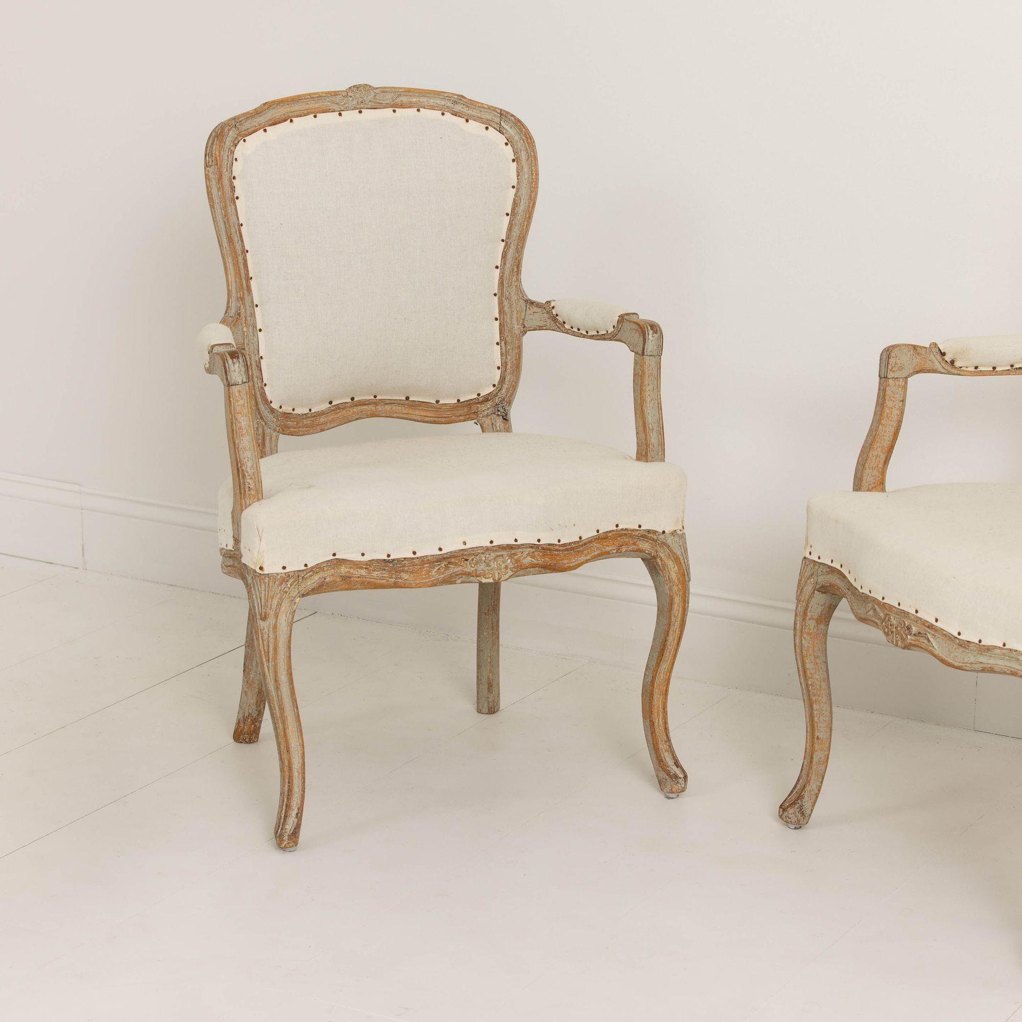 A pair of Swedish armchairs from the Rococo period hand-scraped to the original paint from Lindome, circa 1780. Elegantly shaped frame with beautiful carved flower motif on the chair back and seat front and raised upon cabriole legs.