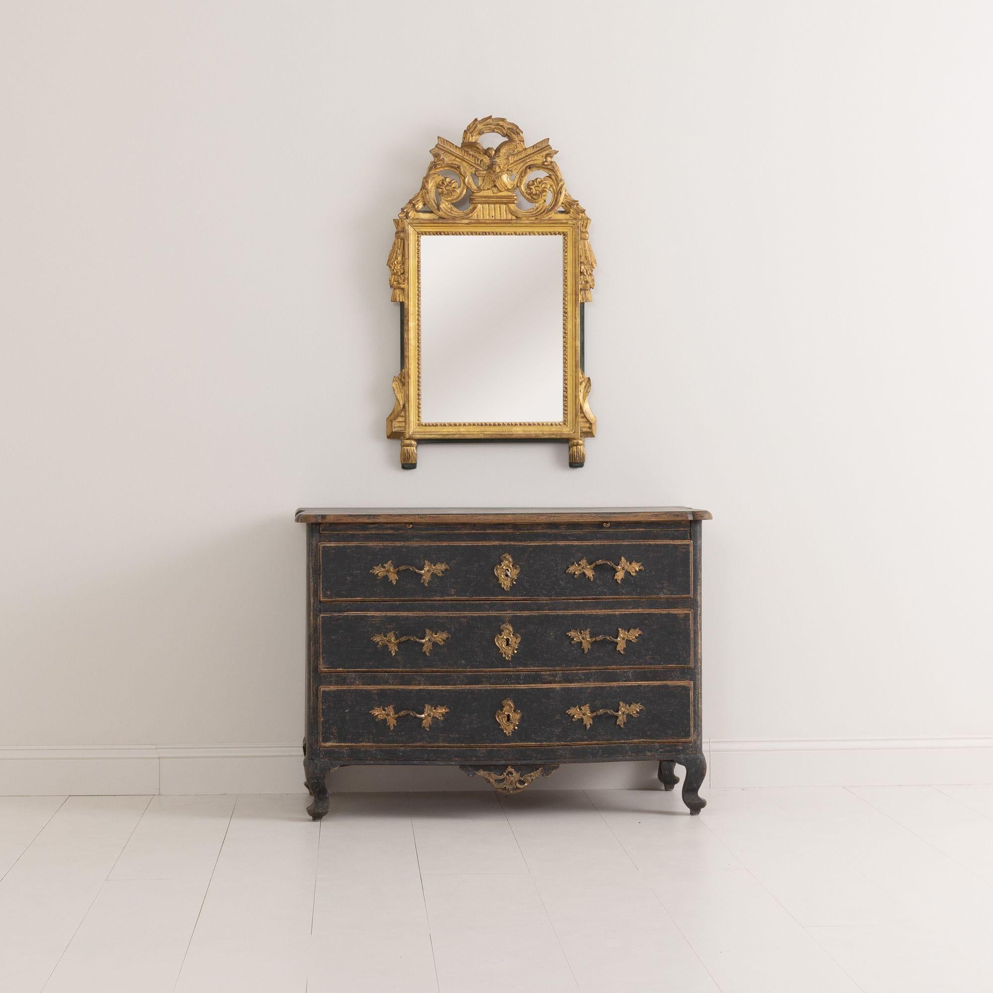 An exceptional 18th century Swedish commode from the Rococo period with original brass hardware, ormolu, and locks. This commode has a serpentine front, shaped top and apron to the front and sides, and is raised on cabriole legs. There is a pull-out