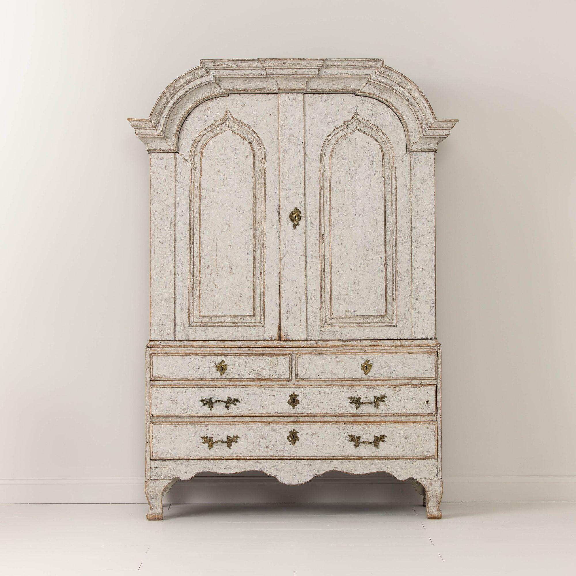 A Swedish painted linen press or armoire from the Rococo period, circa 1760. This piece is made in two parts with original locks and cast brass hardware. This cabinet is beautifully proportioned with a shaped pediment cornice, shaped apron, and