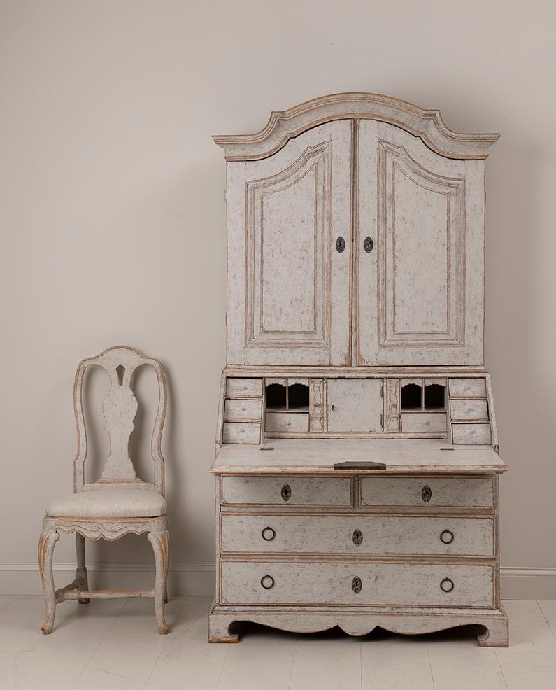 A Swedish secretary with library from the Rococo period, circa 1760. The upper section has two shaped shelves and a multitude of small drawers. The slant front opens to reveal six waterfall shaped drawers and a center door with pigeon holes. Below