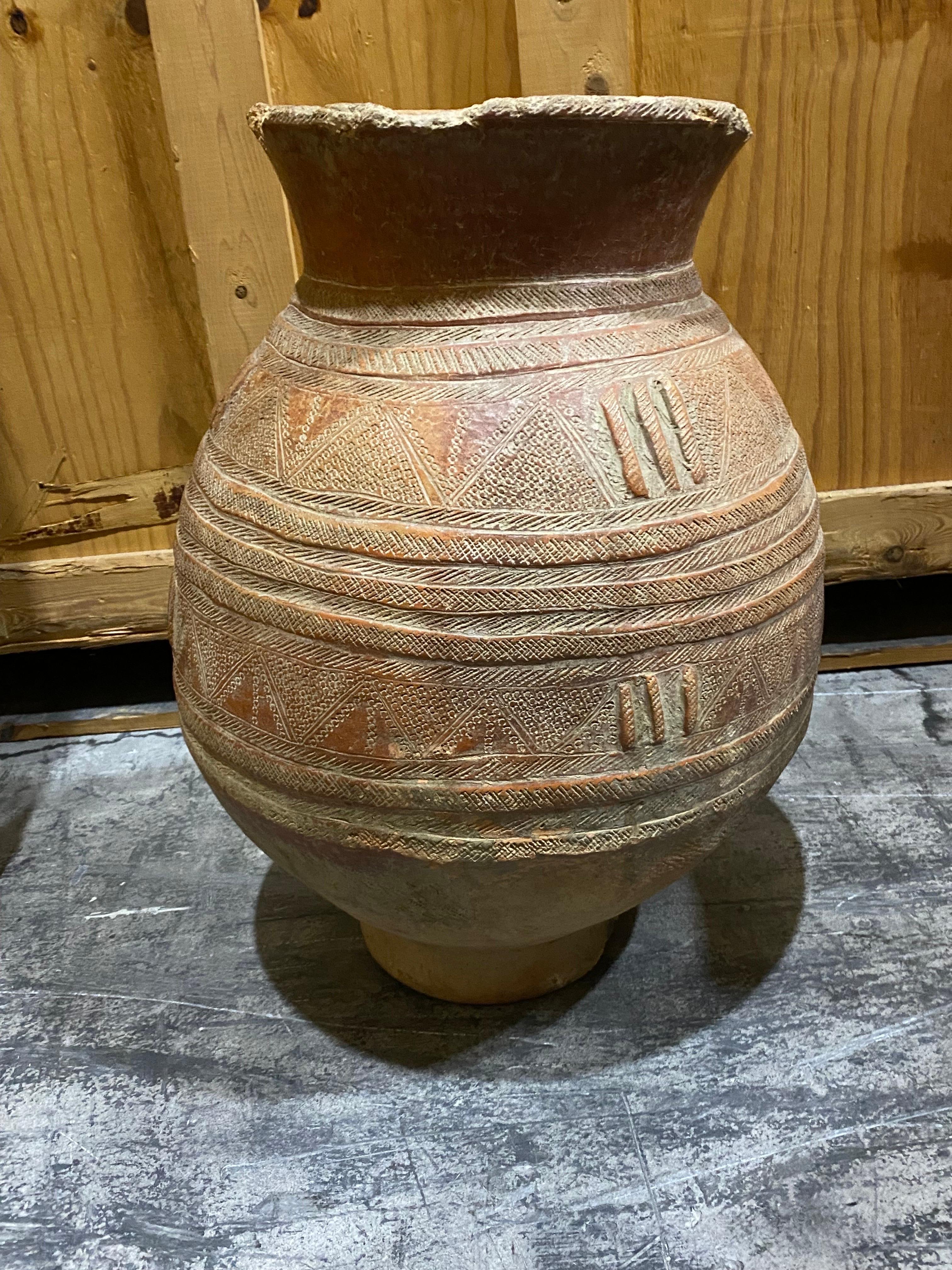 18th C. Terracotta Jar with elaborate incised design in a worn reddish finish. 
Potentially much older, the design consists of hand molded lines running horizontally with cross hatch design incised between a repeating motif of three molded vertical