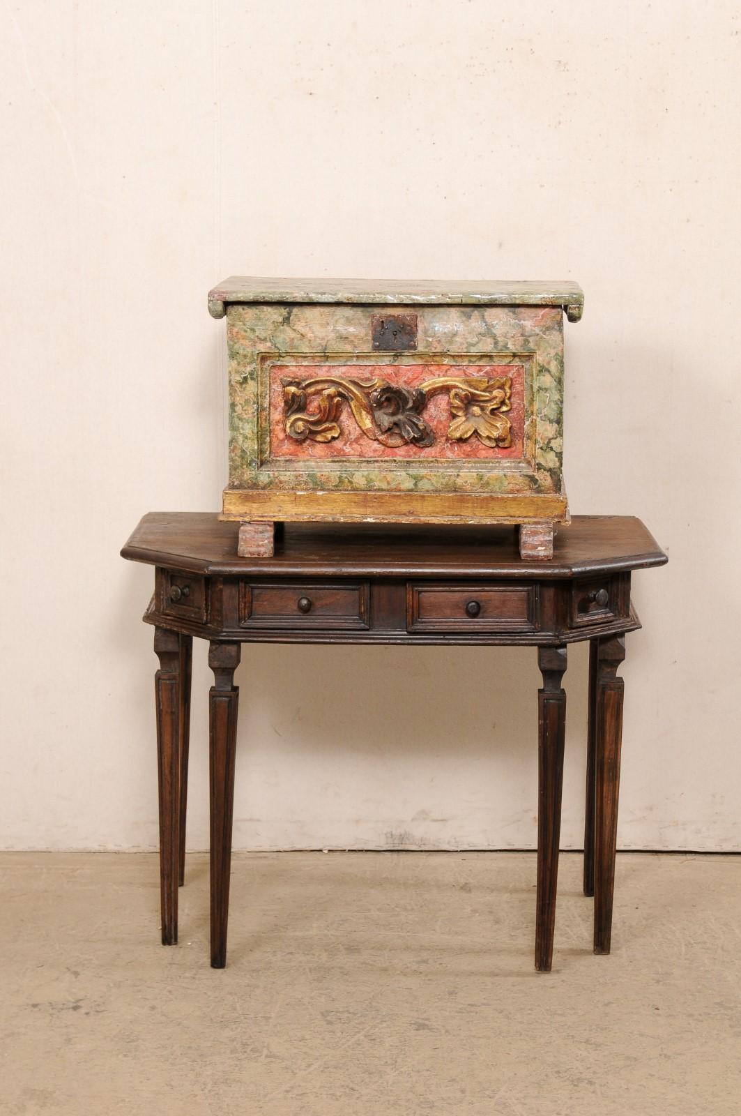 A Venetian Italian box with its original finish, from the 18th century. This antique wood box from Italy is rectangular in shape with a raised foliate carving adorning its front facade. It retains its original, hand-painted faux marble finish and