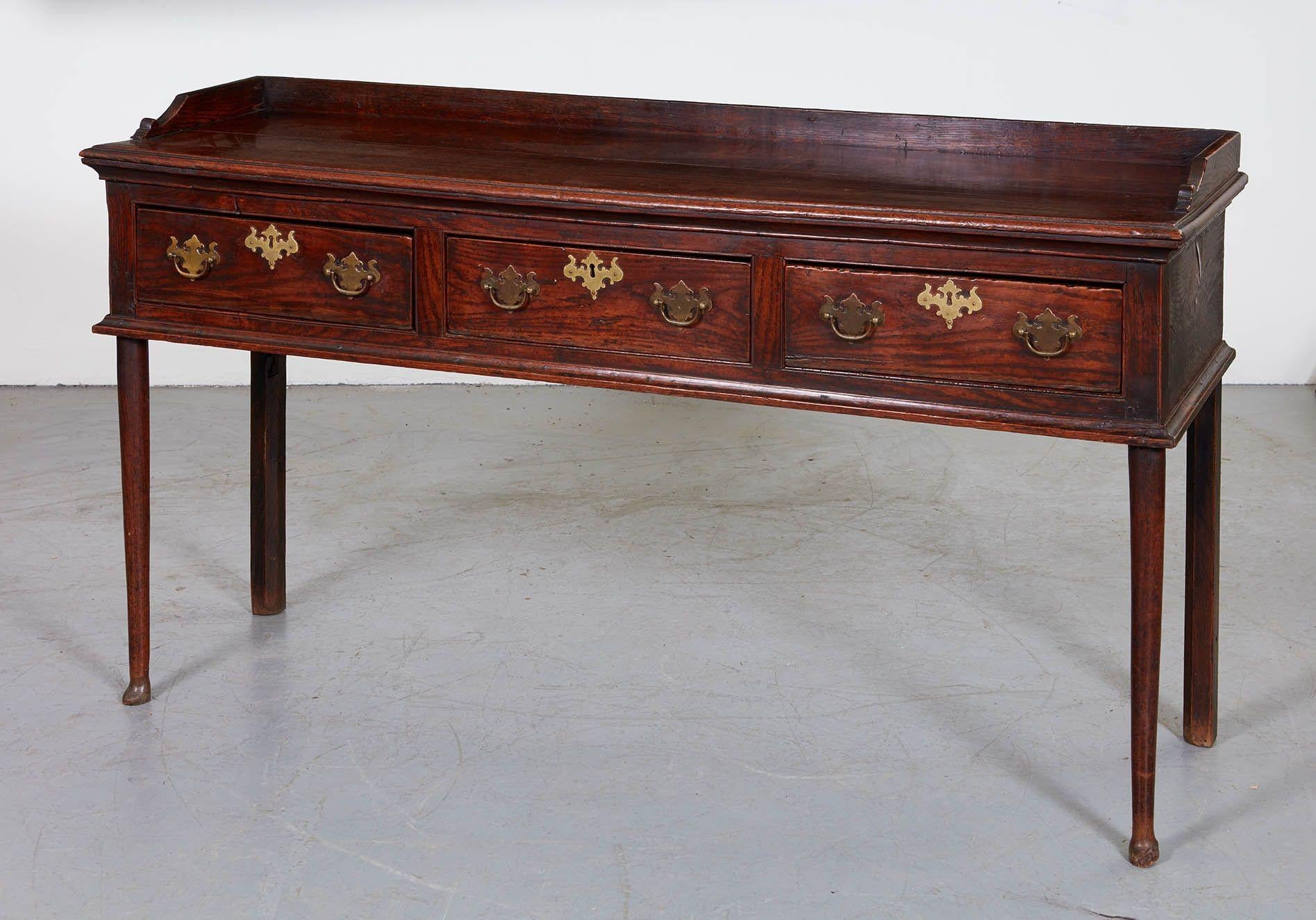 An elegant 18th century Welsh dresser having thin body of three drawers over slim legs, the front legs turned, tapered and ending in pad feet, having two plank top with backsplash molding, and ogee molding to top and bottom of drawers.