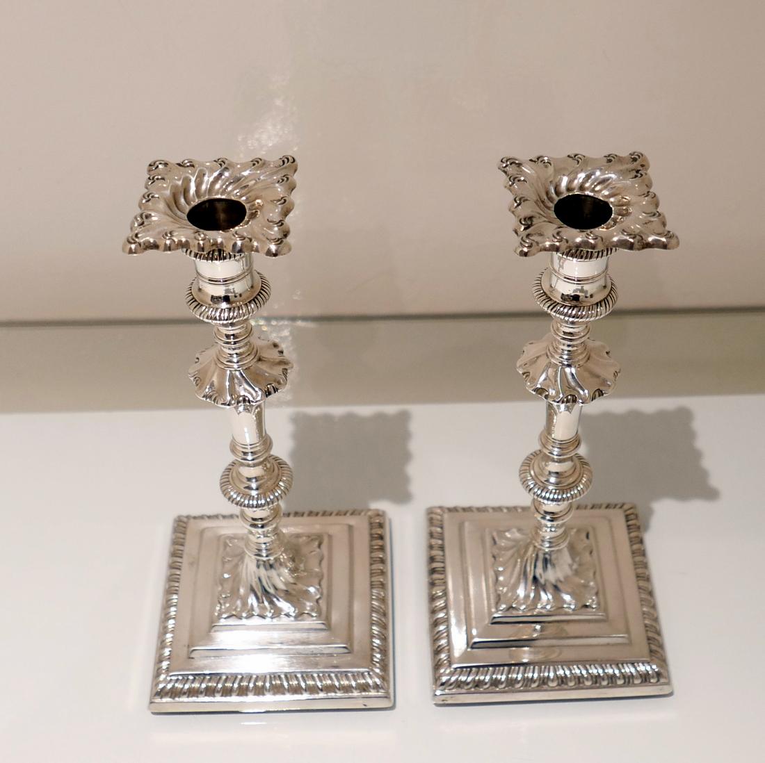 A very elegant pair of silver Georgian candlesticks decorated with gadroon borders and swirl fluted “stepped” bases. The central stems have delightful contemporary crests and the detachable nozzles have additional swirl flute decoration, 18th