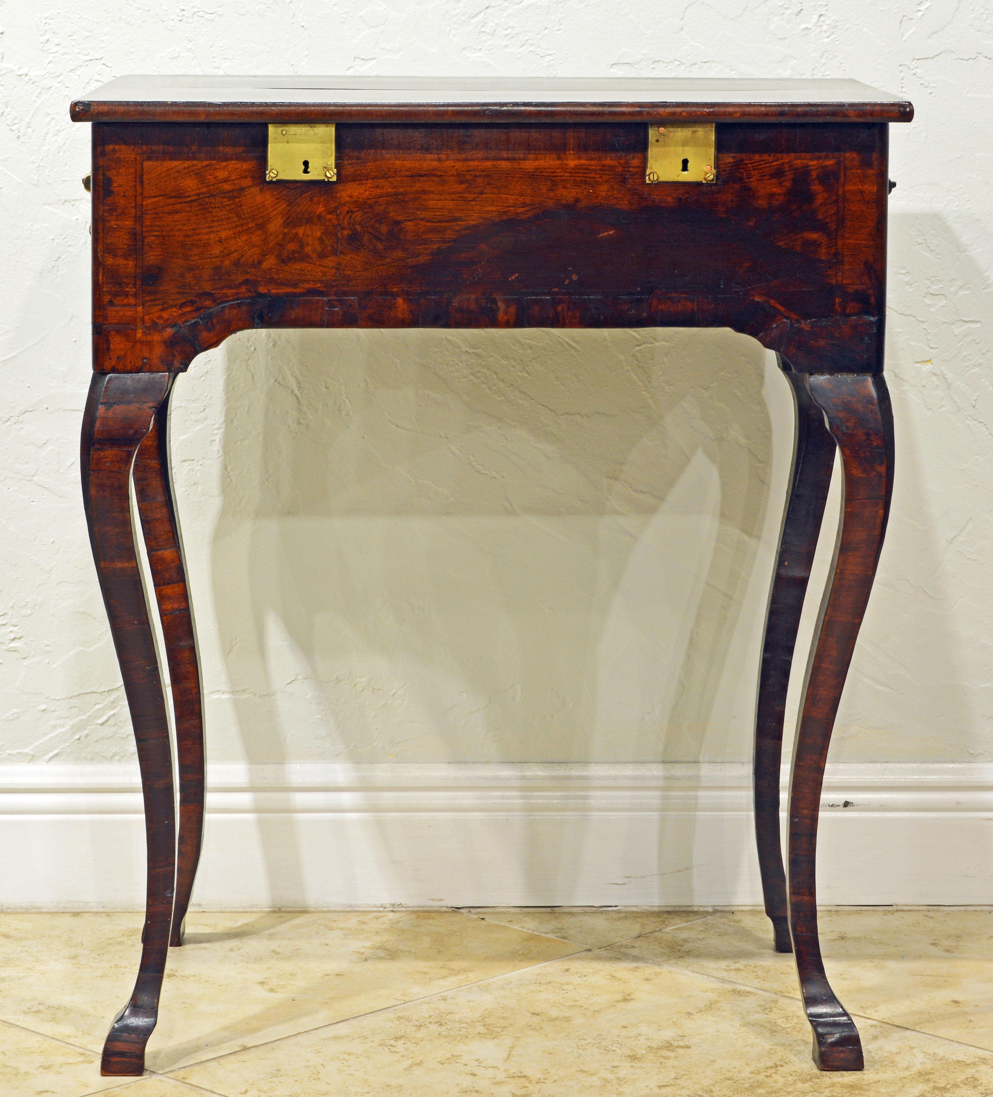 This unusual Spanish Rococo table with cabriole legs likely dates to the second part of the 18th century. It features a top that opens up to a paper lined storage compartment with two brass locks indicating the use for valuables. Each end is mounted