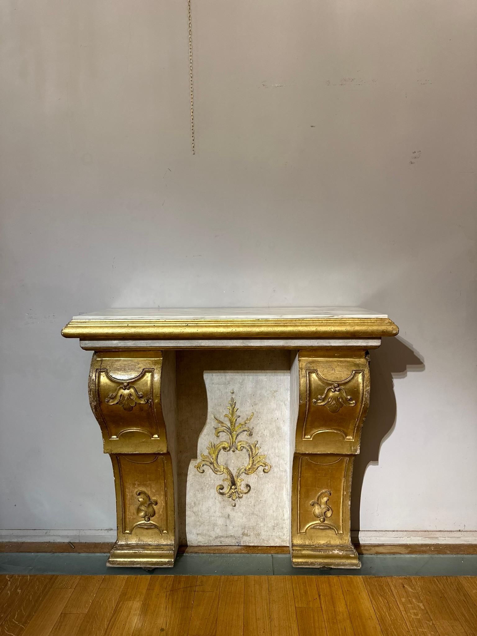 Refined altar and shelf consolle, made of carved and gilded wood. The central space is also made of carved and painted wood with a classic Louis XIV style golden decoration depicted in the centre. The console top is in Carrara marble. The