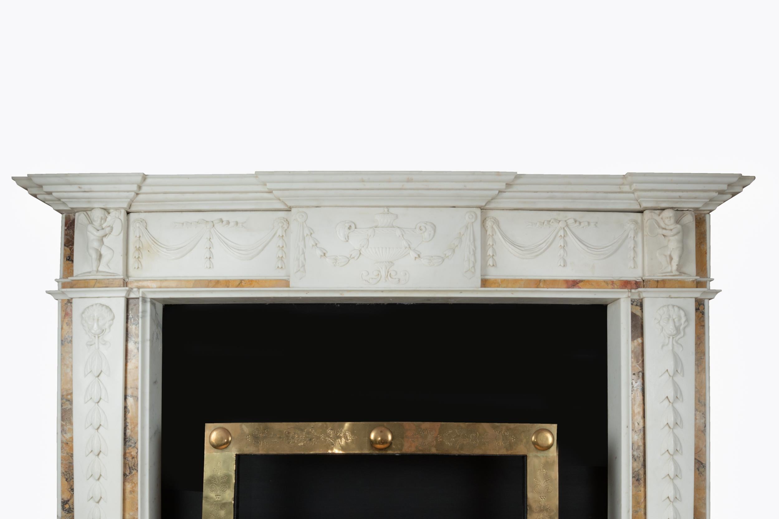A heavily decorated chimneypiece of white statuary and sienna marble. The central tablet is sculpted with very a finely carved urn flanked with ram’s heads, drapery and foliage which epitomizes the refinement and elegance Adam brought to his work.