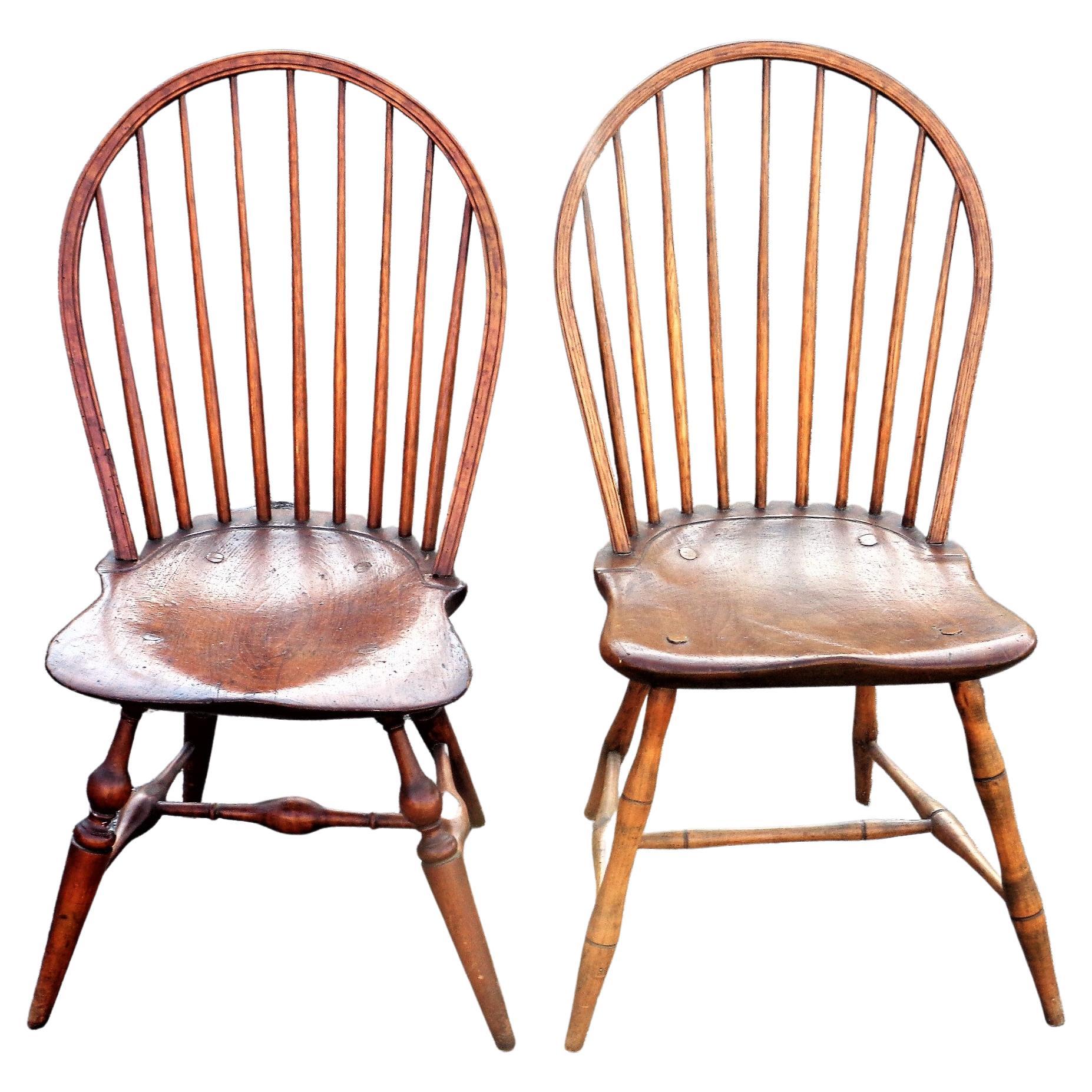 A near pair of antique American bow back Windsor side chairs in nicely aged color and original period construction. One chair has darker finish, a slightly more dished saddle seat and bolder turnings at legs / stretchers. Circa 1790-1800. Look at