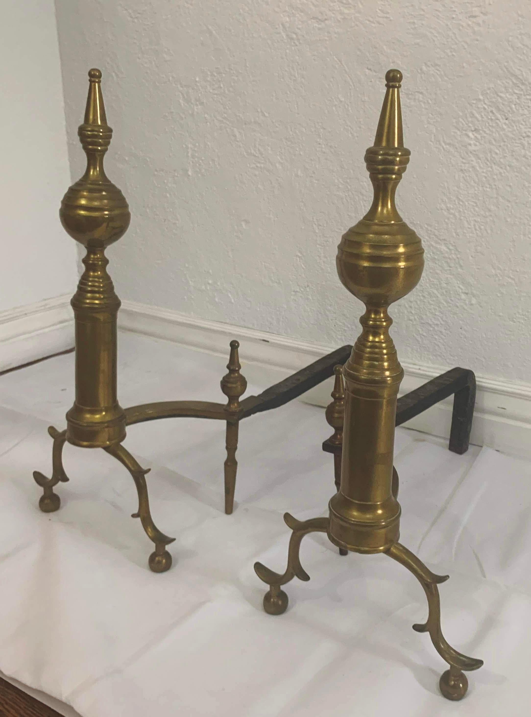 Late 18th century American New York steeple top andirons with S-scrolled legs and spurs ending in ball feet. The body is brass with hand-wrought iron shaft.

Dimensions for 1 andiron 
22
