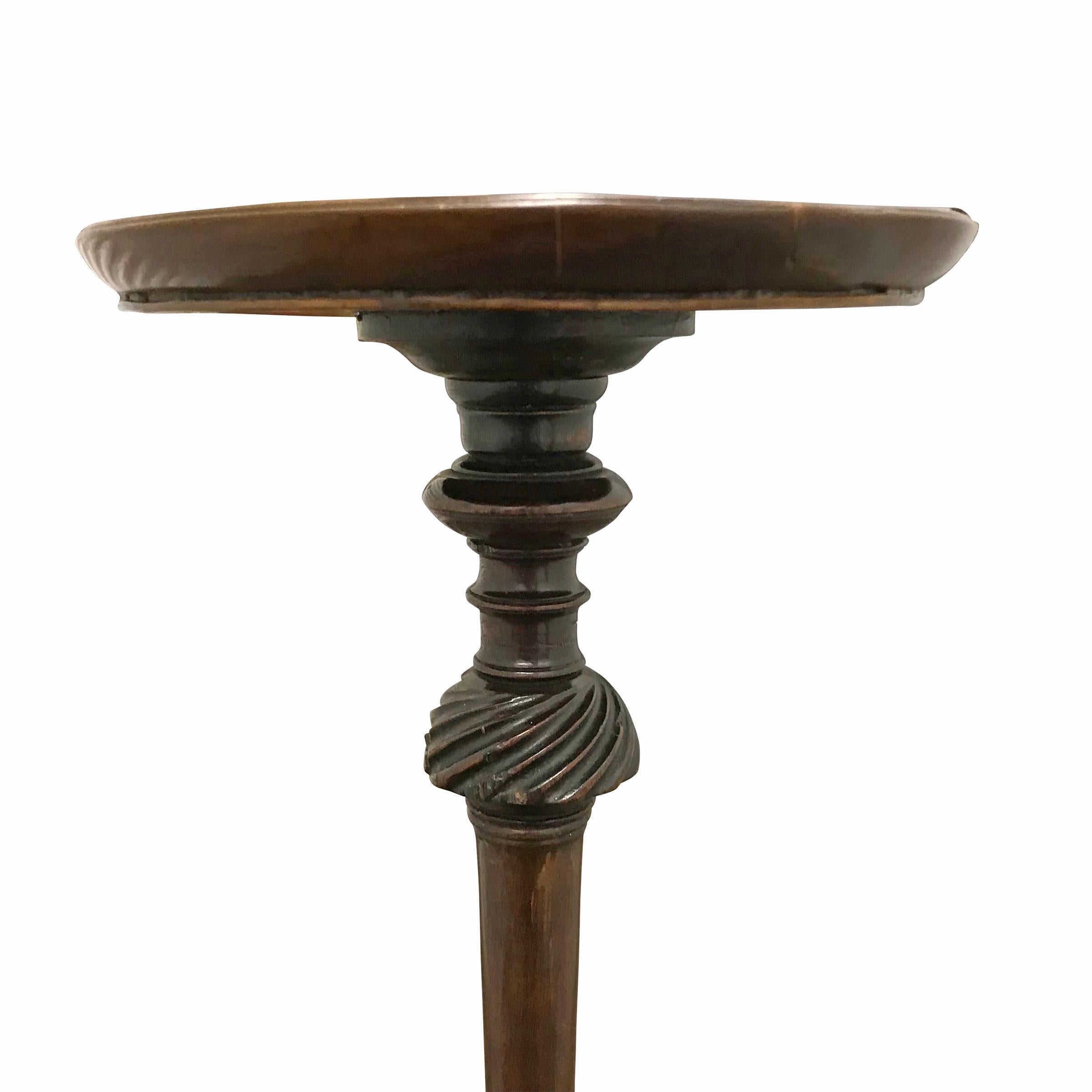 An 18th century Queen Anne mahogany candle stand with a top turned of one piece of wood with a shallow lip edge, wonderfully turned columnar turned pedestal with multiple turned knuckles, resting on a tripod leg base ending in Classic Queen Anne pad