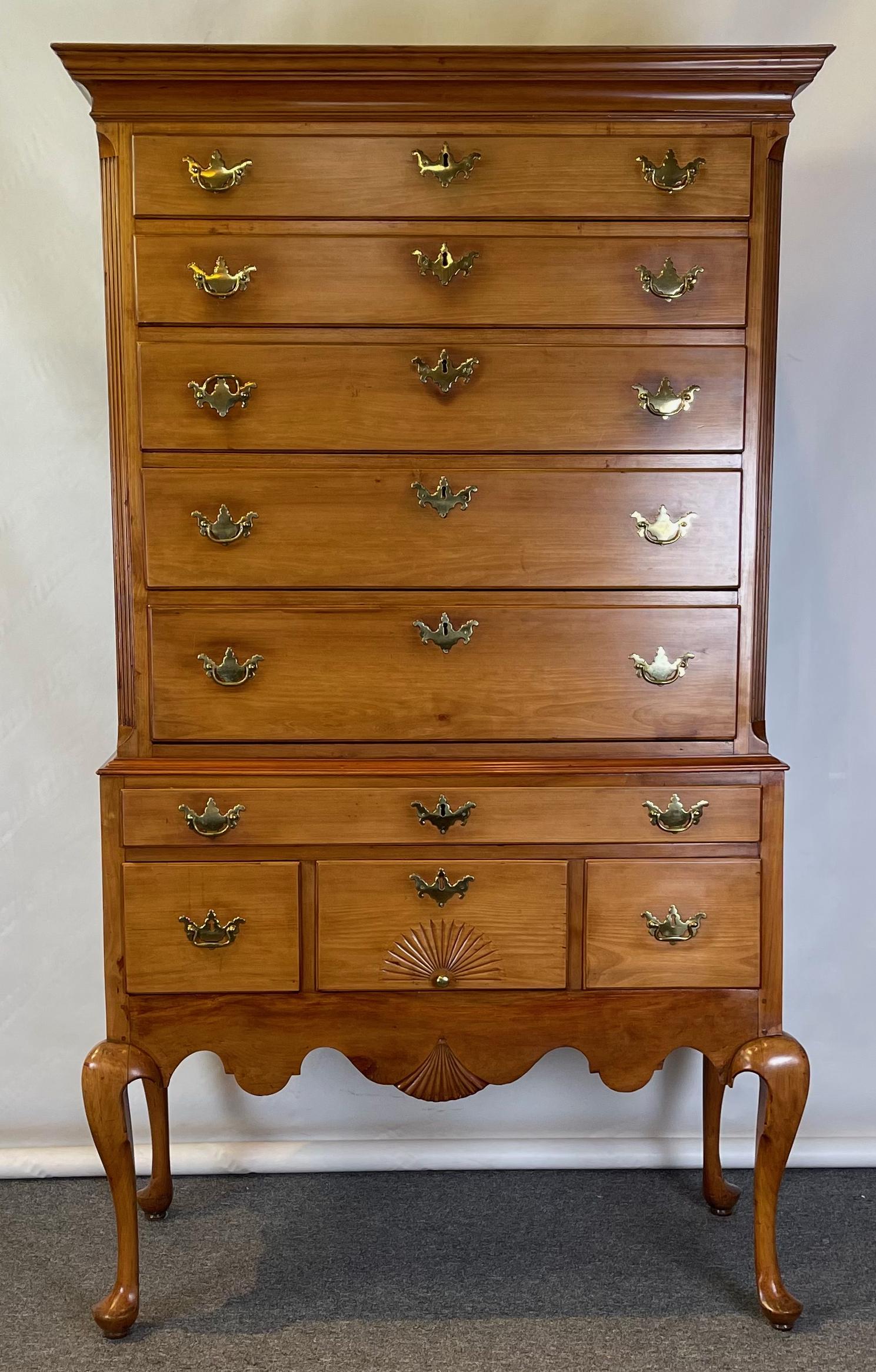 An 18th Century American Queen Anne cherrywood flat top graduated highboy from coastal New England with delicate shell detail and carved apron standing on exceptionally bold and elegant cabriole legs with pad feet.