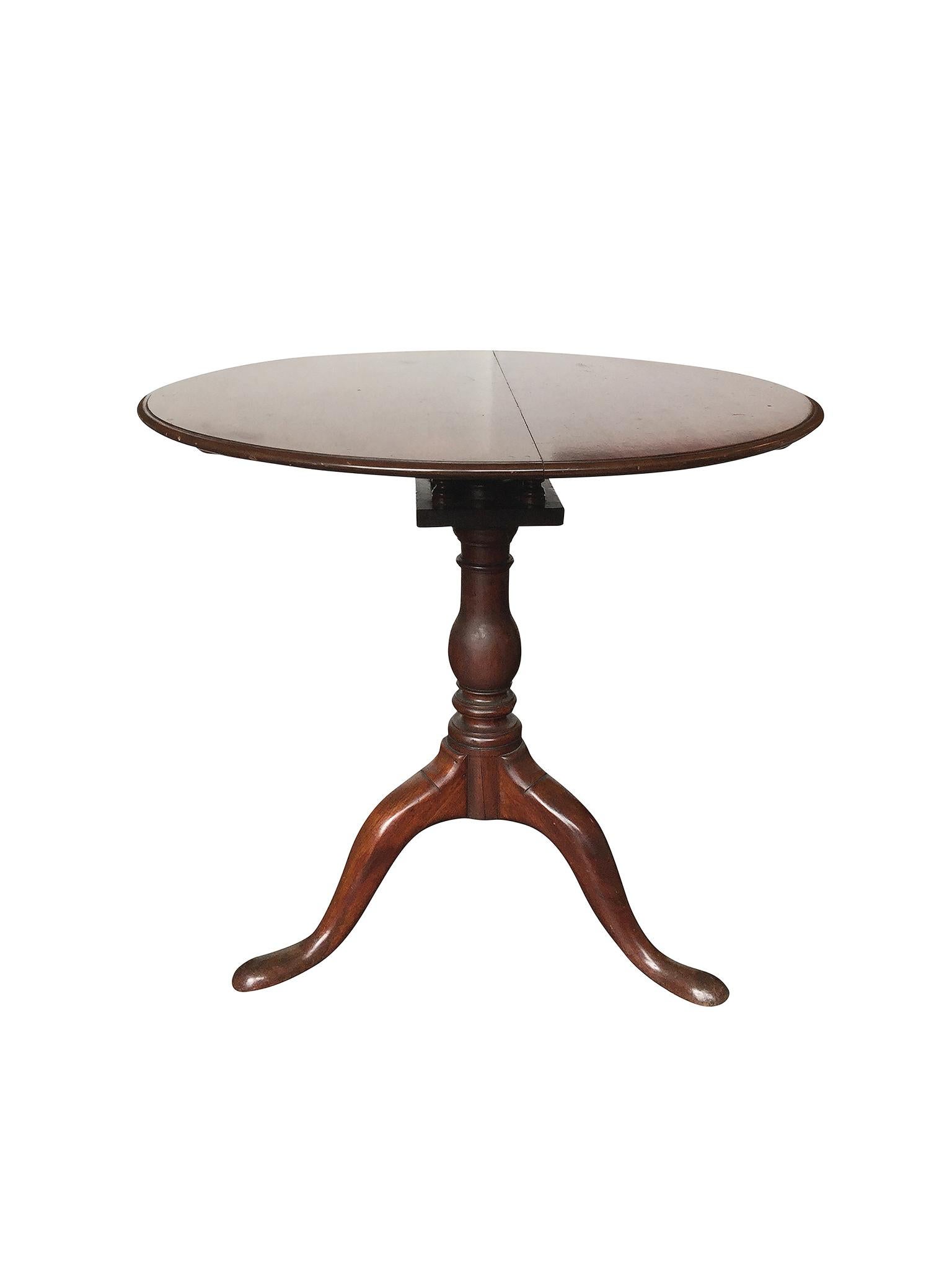 This American Chippendale tilt-top tea table was handcrafted in the 18th century from mahogany wood. It's comprised of a bevelled circular top and vase-form pedestal tripod base that culminates in snake feet. A 