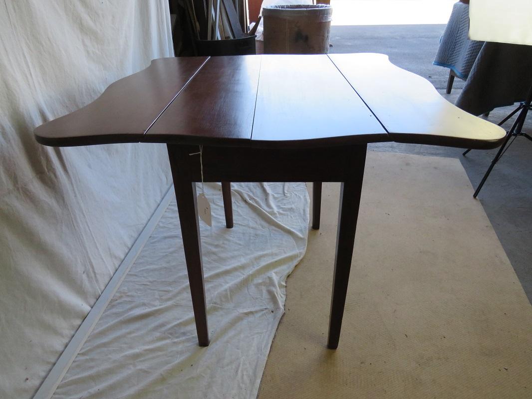 18th century American Hepplewhite cherry drop leaf table, circa 1780, having a shaped top with fluted shallow leaves, raised on square tapering legs; in deep, warm patina.

The table is in great condition, though note that one of the draw supports