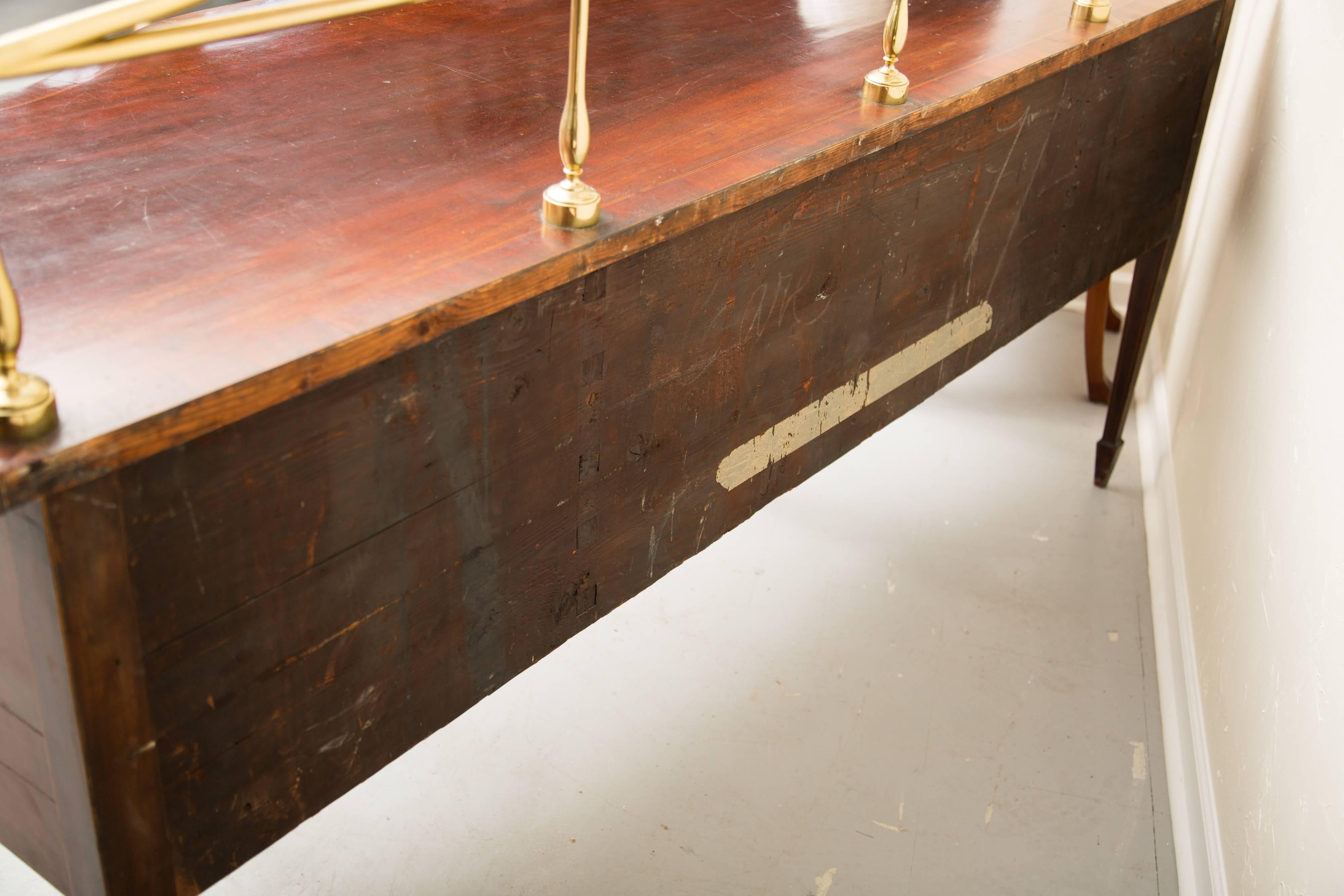 This is a fine American mahogany sideboard, graceful and elegant, in spite of its size. The top with straight edge and bow-front centre flanked with recessed configurations and containing a bold and elaborate brass gallery over a long central drawer