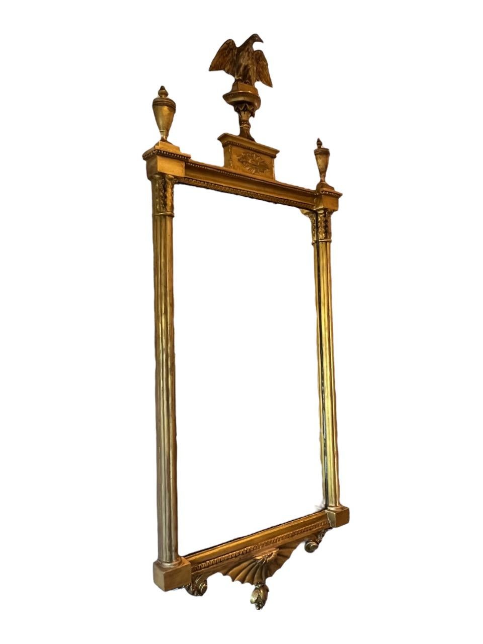 Behold an exquisite relic from the 18th century, a grand manifestation of American Federal period craftsmanship—an opulent, large carved-wood mirror adorned with resplendent gold gilt accents. At its crest proudly perches a majestic patriotic eagle