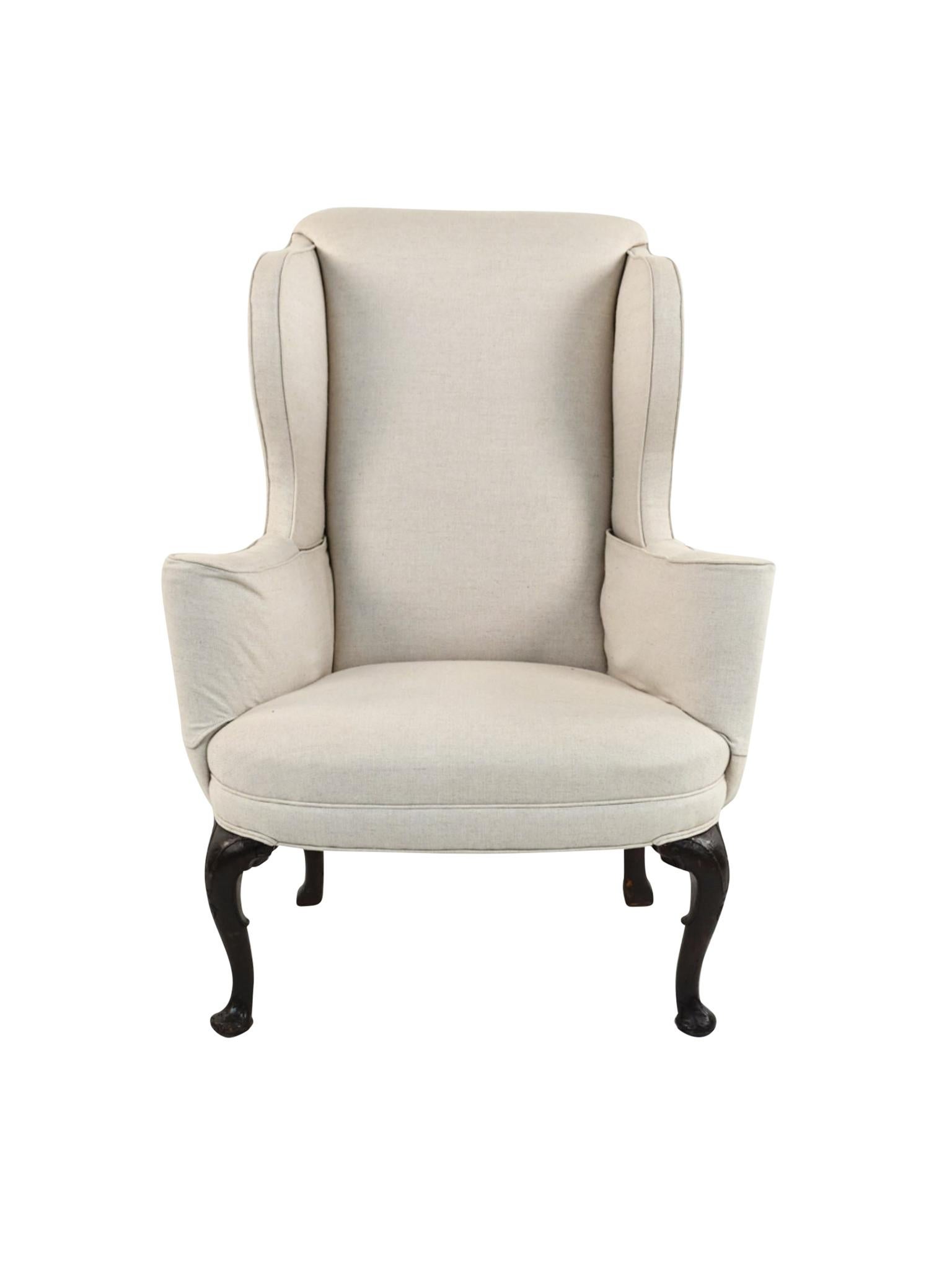 This American Queen Anne wingback armchair was hand-crafted in the 18th century. It has been restored and reupholstered with a beige twill linen from Schumacher. We love the combination of the new fabric and the beautifully aged, hand-carved