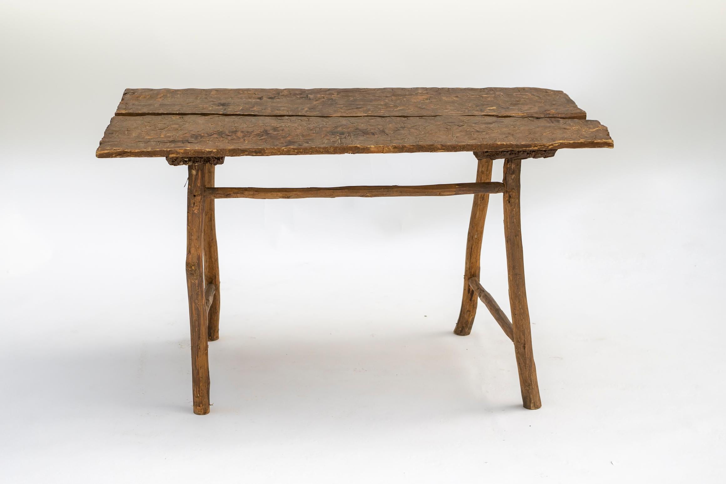 Une table du XVIIIe siècle magnifiquement usée par le temps, fabriquée à la main avec des planches taillées à l'emporte-pièce, mettant en valeur la beauté brute et organique de la charpenterie ancienne. Le plateau de la table, formé d'épaisses