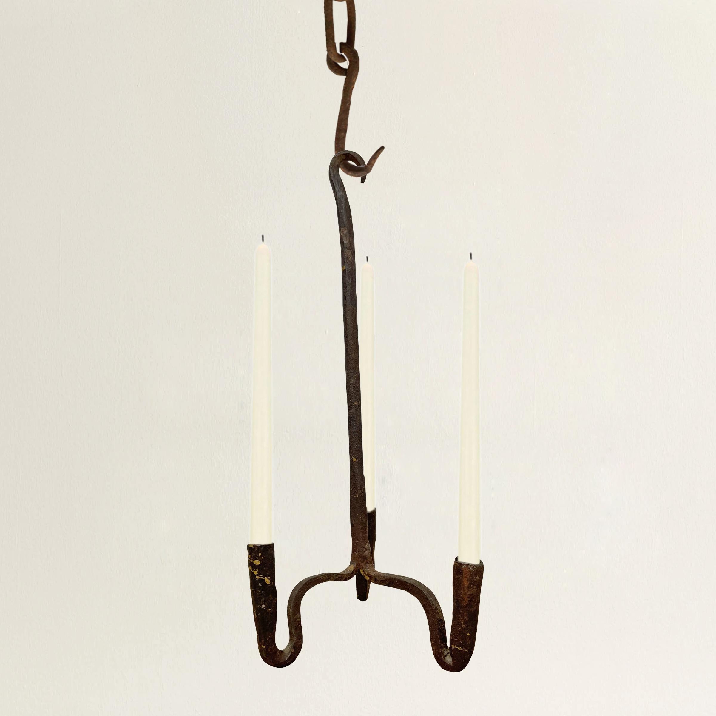 A charming petite late 18th century American wrought iron chandelier with three curved arms uniting at a central down rod with a curved hook on top. Fixture has never been electrified.