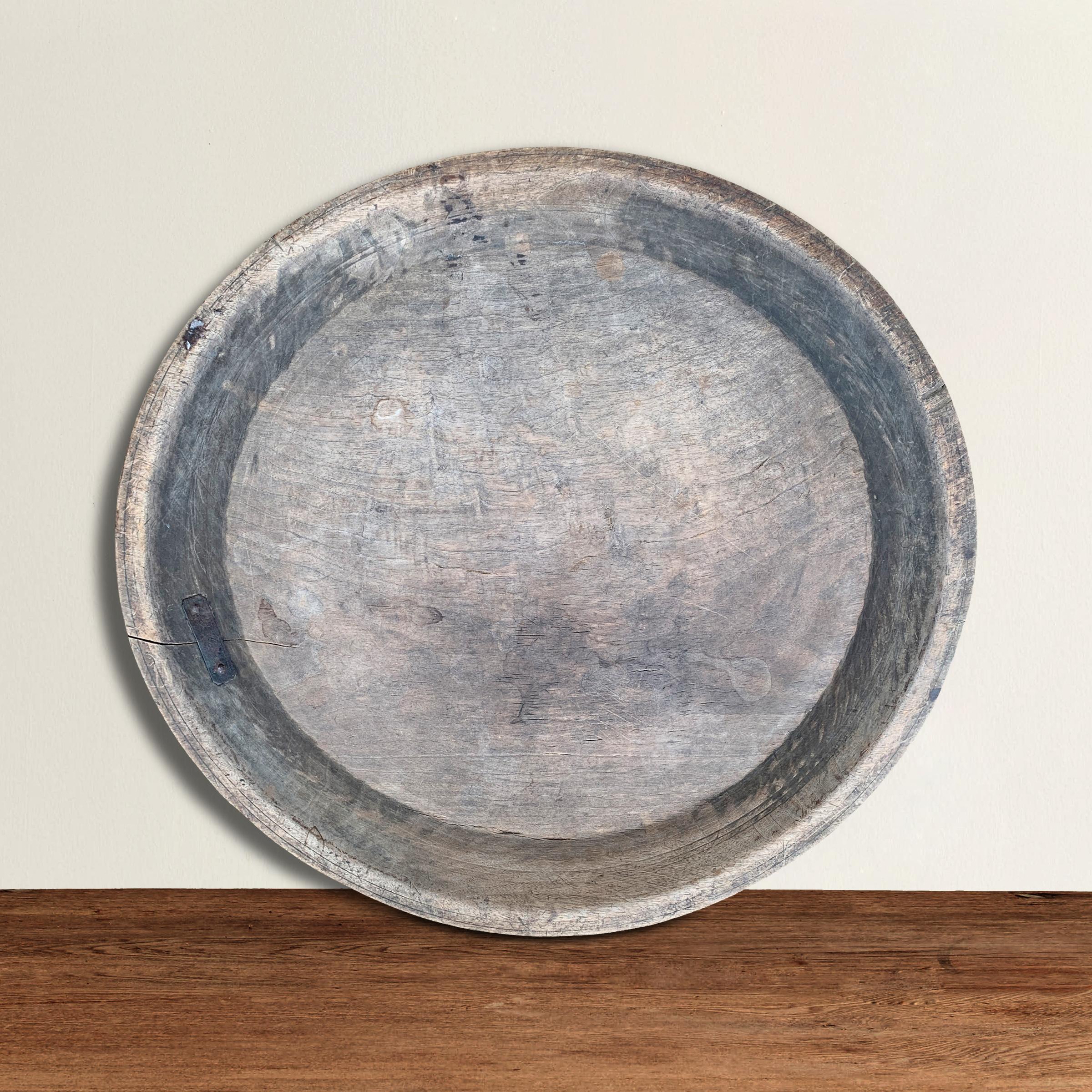 An incredible 18th century American turned wood platter with a wide rim, wonderful incised lines on the exterior, an old repair, and a weathered patina only time can provide.