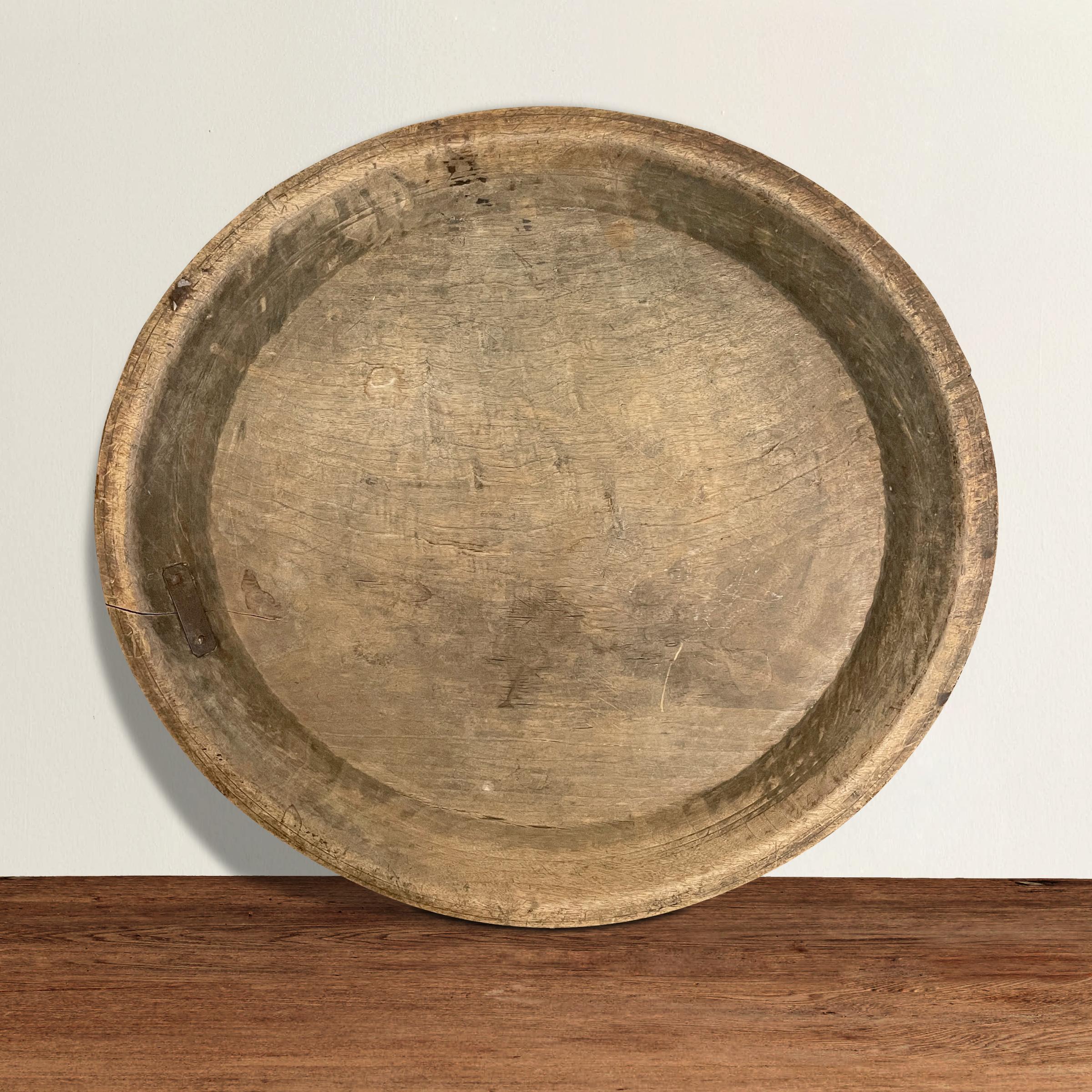 An incredible 18th century American turned wood platter with a wide rim, wonderful incised lines on the exterior, an old repair, and a weathered patina only time can provide. Perfect on your kitchen island filled with fruits and veggies, but also