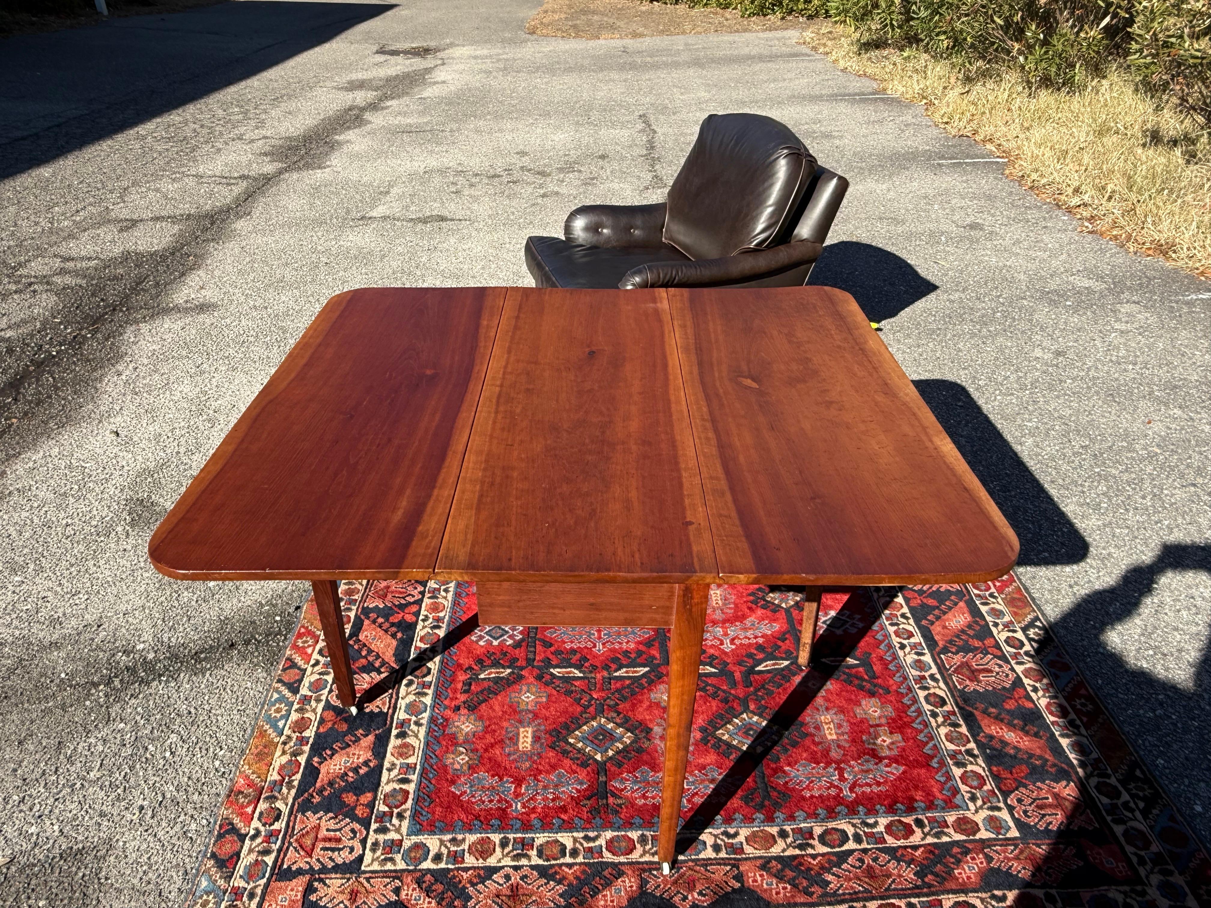 Table de salle à manger en noyer de style fédéral avec un grain de bois prononcé, des pieds carrés effilés terminés par des roulettes en laiton et en porcelaine, et une construction à queue d'aronde. Très bon état général, avec une belle patine