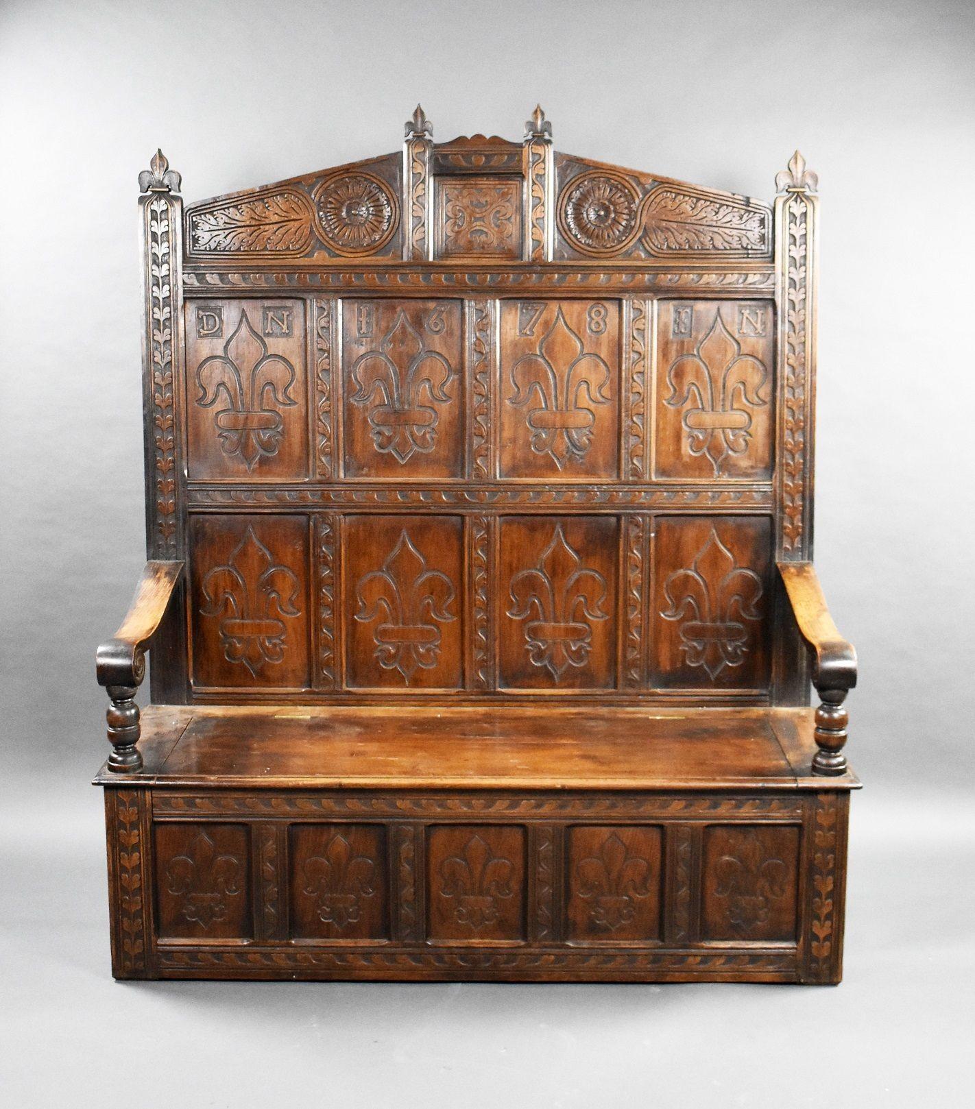 18th Century and later carved oak high back settle in good condition with fleur de lis panels over a hinged seat with five panels below.
